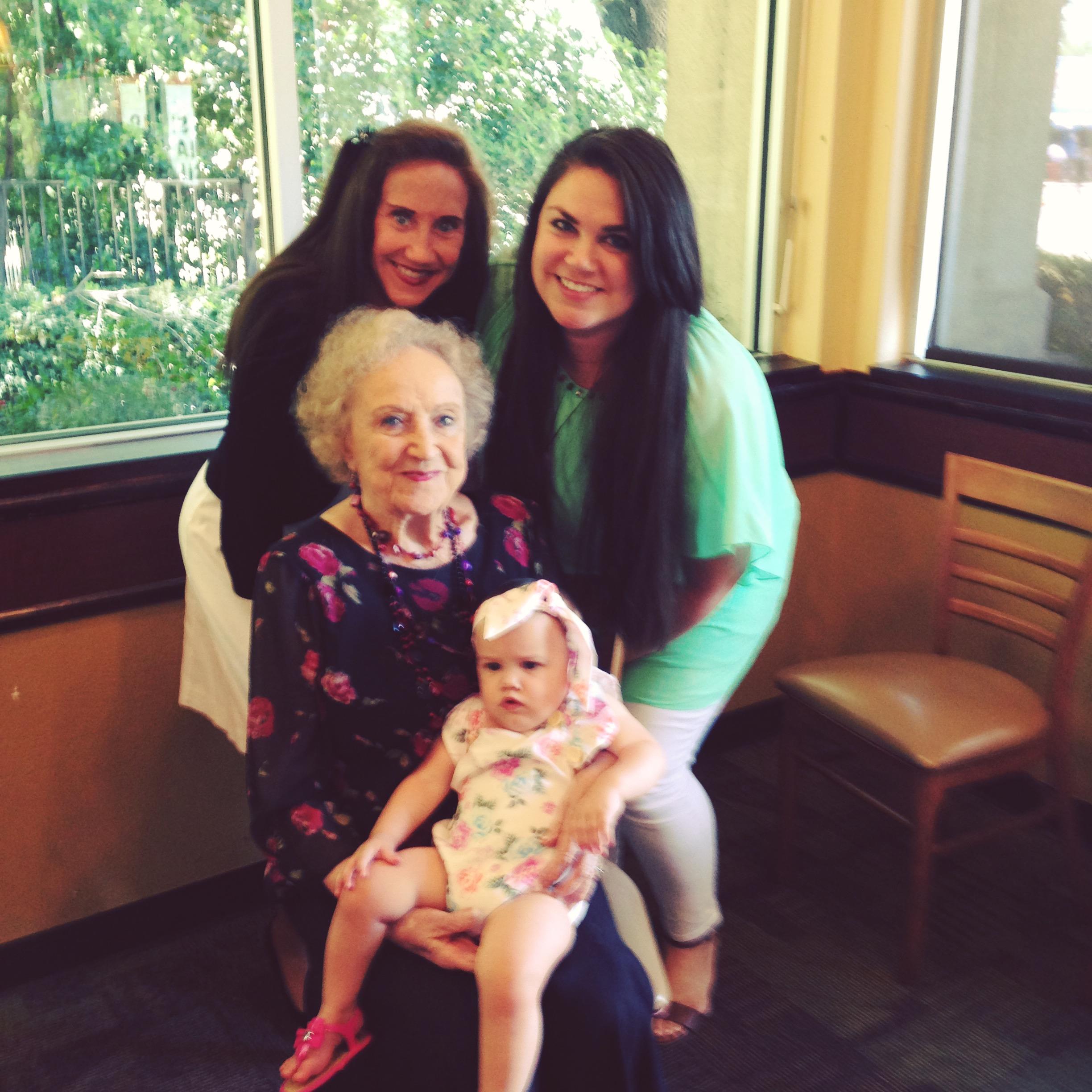 Four generations of a family gather happily at a restaurant, creating lasting memories together.