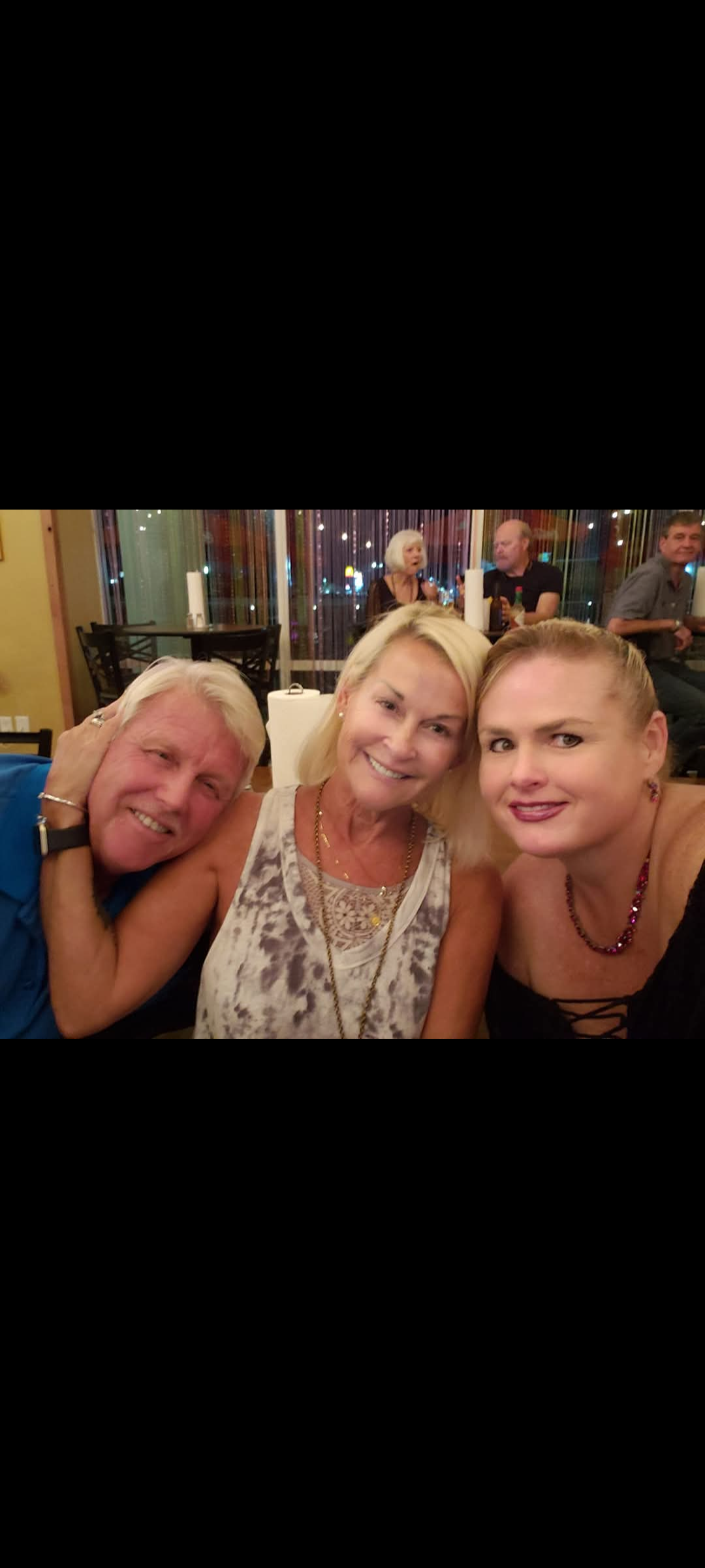 Friends smile and pose for a selfie while enjoying their time at a vibrant restaurant setting.