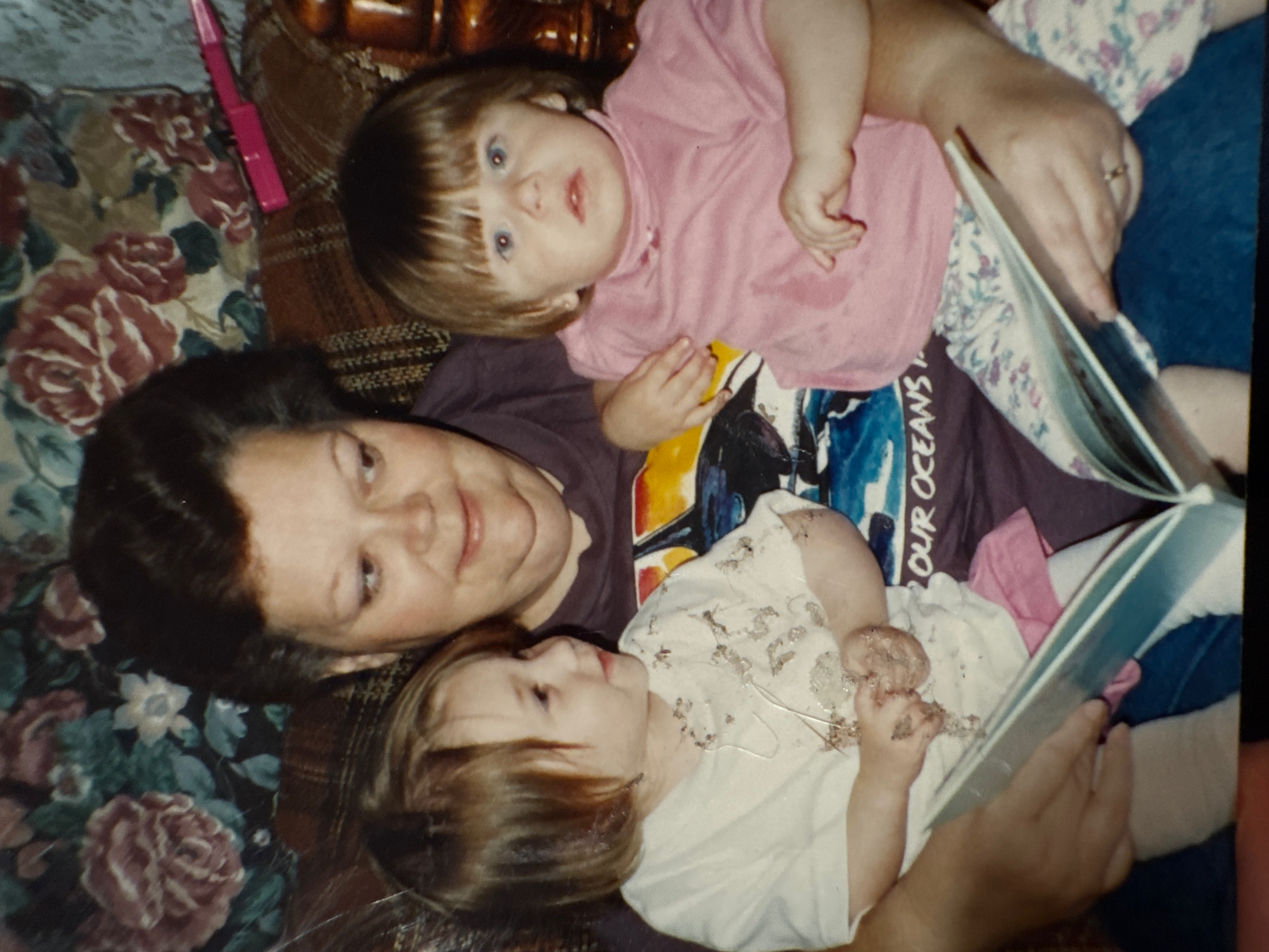A grandmother enjoys reading a storybook with her grandchildren in a warm living room setting.