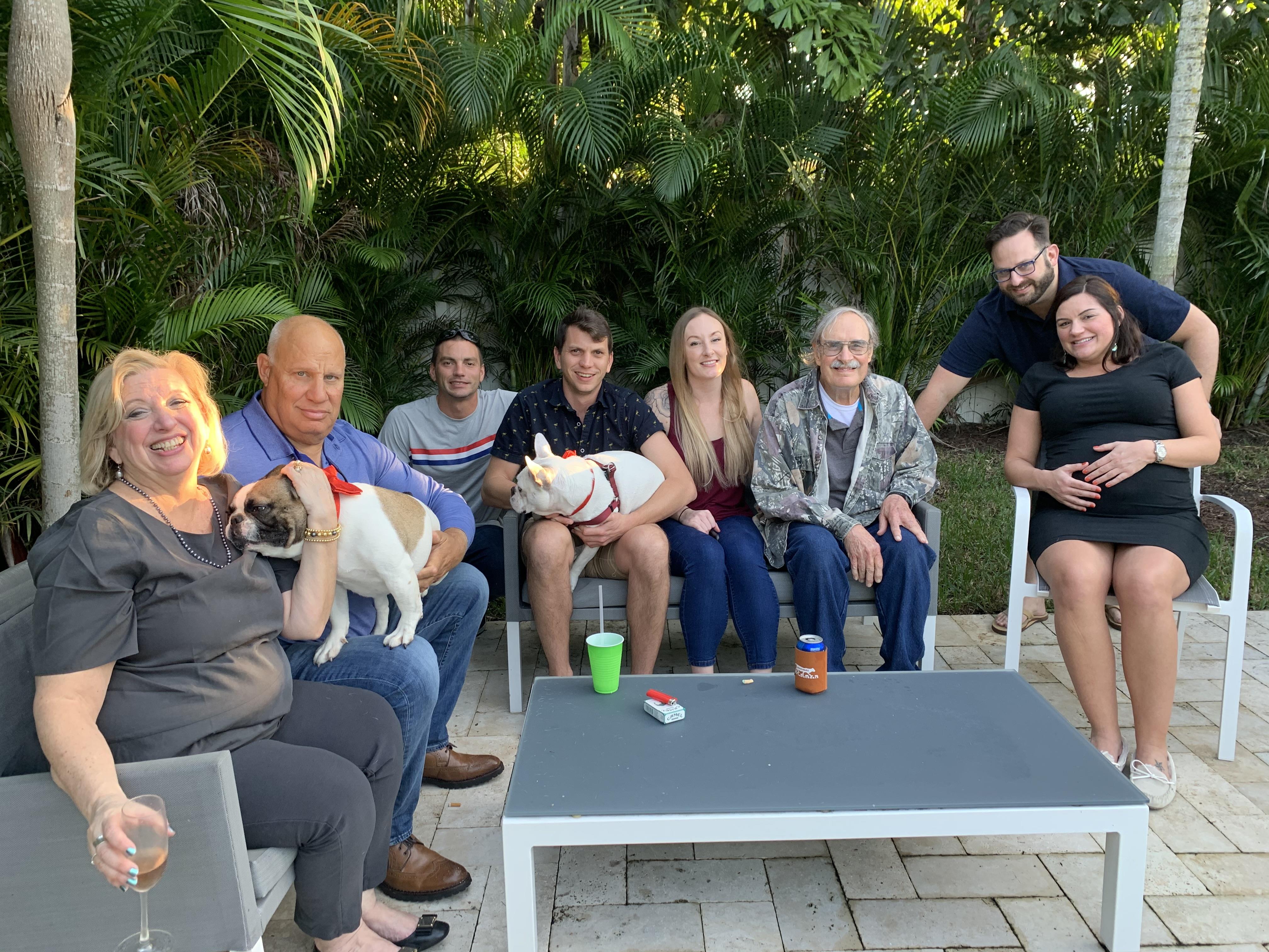 A family enjoys each other's company in a lush backyard with pets on a warm afternoon.