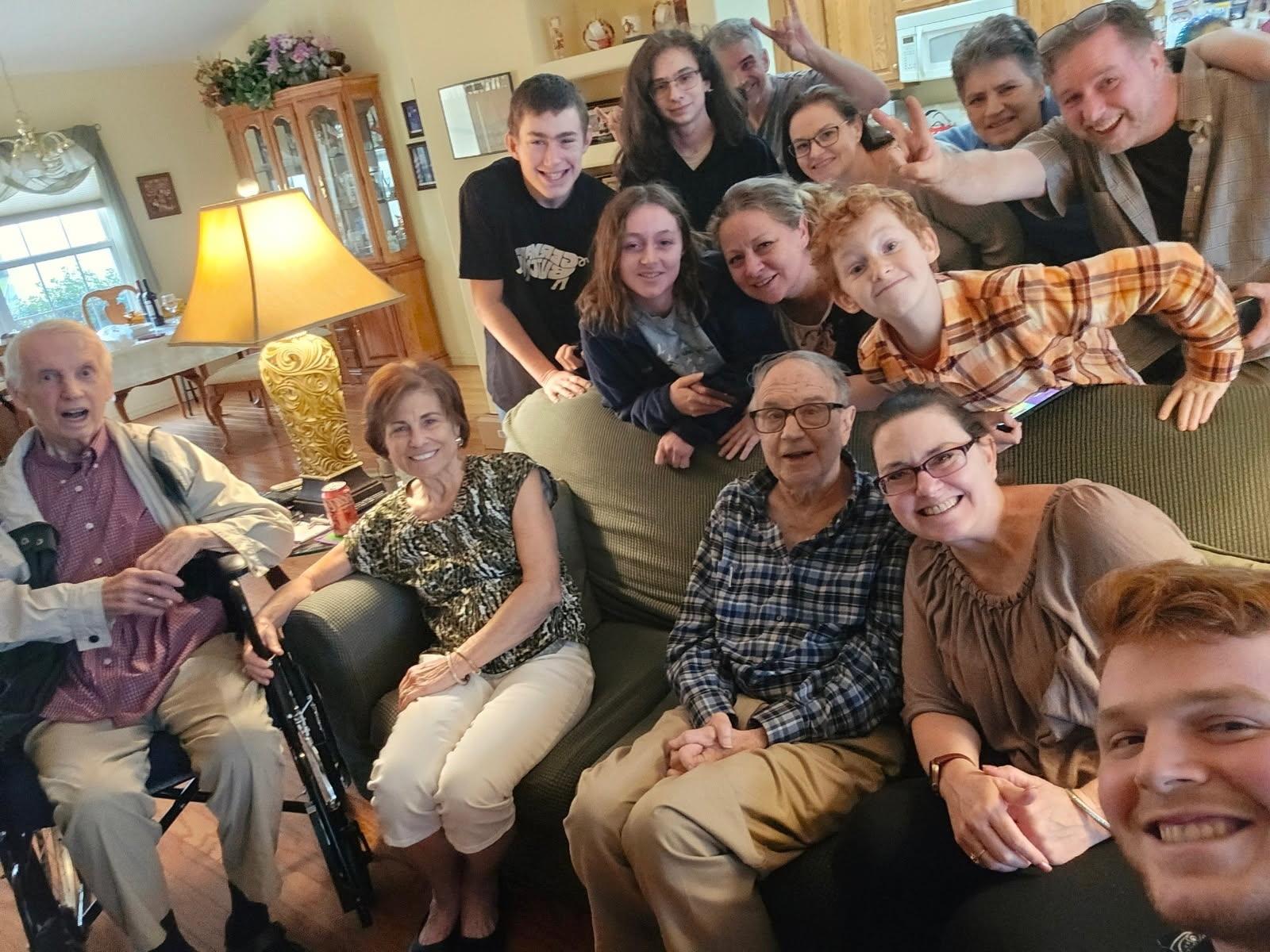 Multiple family members pose happily together in a cozy living room, enjoying their time.
