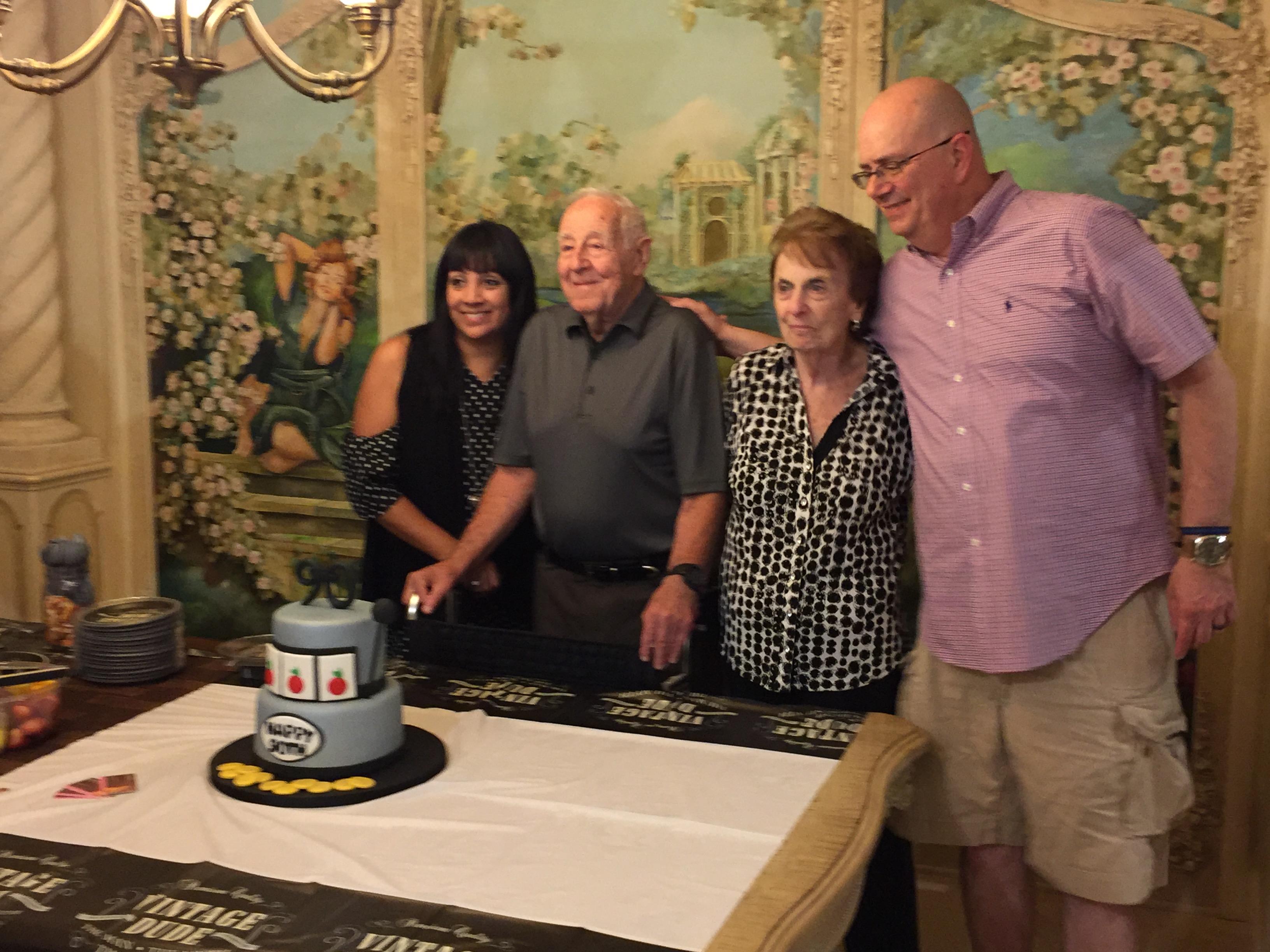 Family gathers to celebrate a special birthday in an elegant room with a decorated cake.