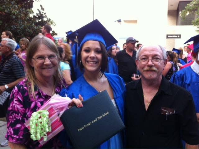 Celebrating a high school graduation with family members in a joyful outdoor atmosphere.