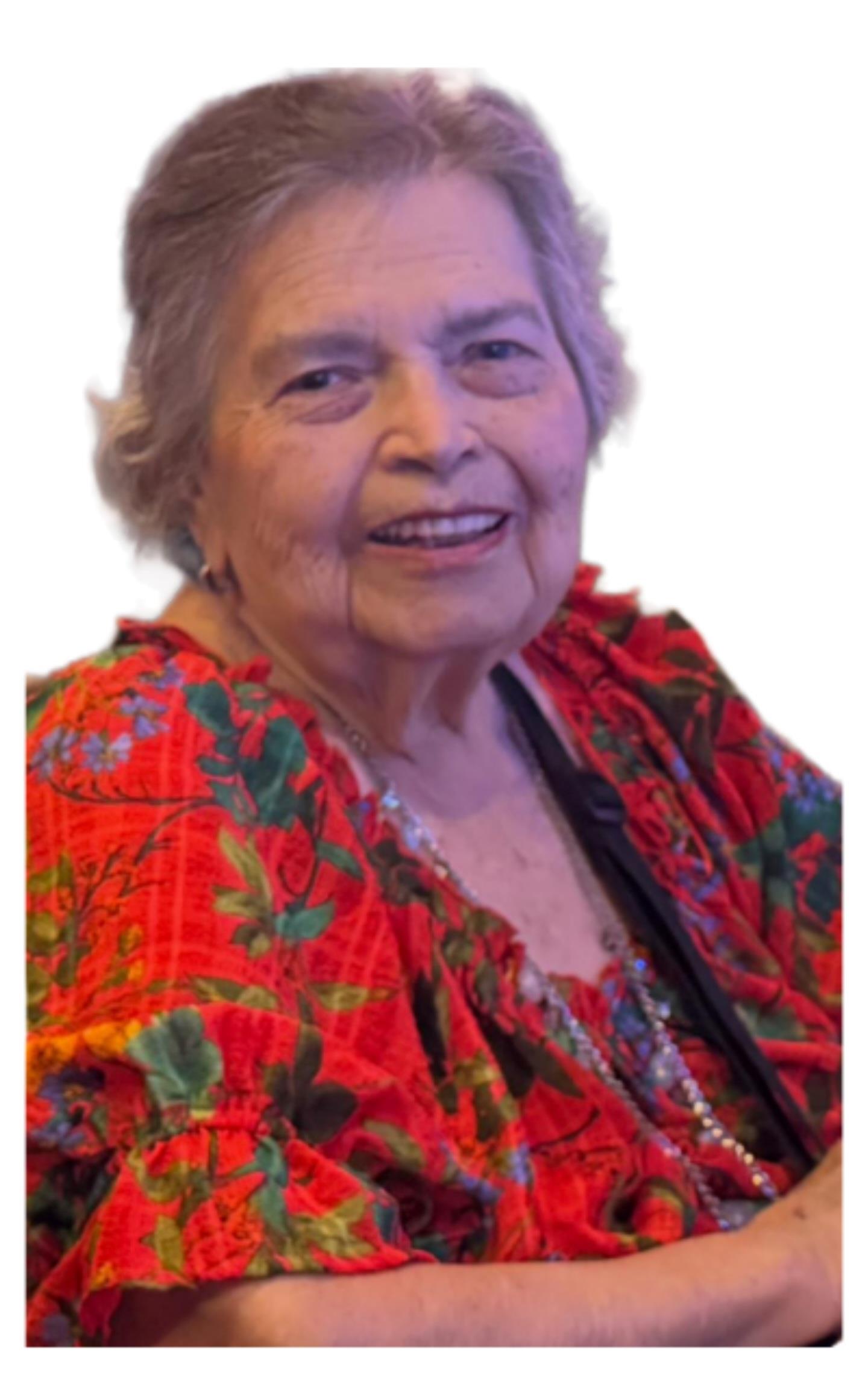 A joyful elderly woman in a colorful dress smiles at a family gathering, radiating warmth.