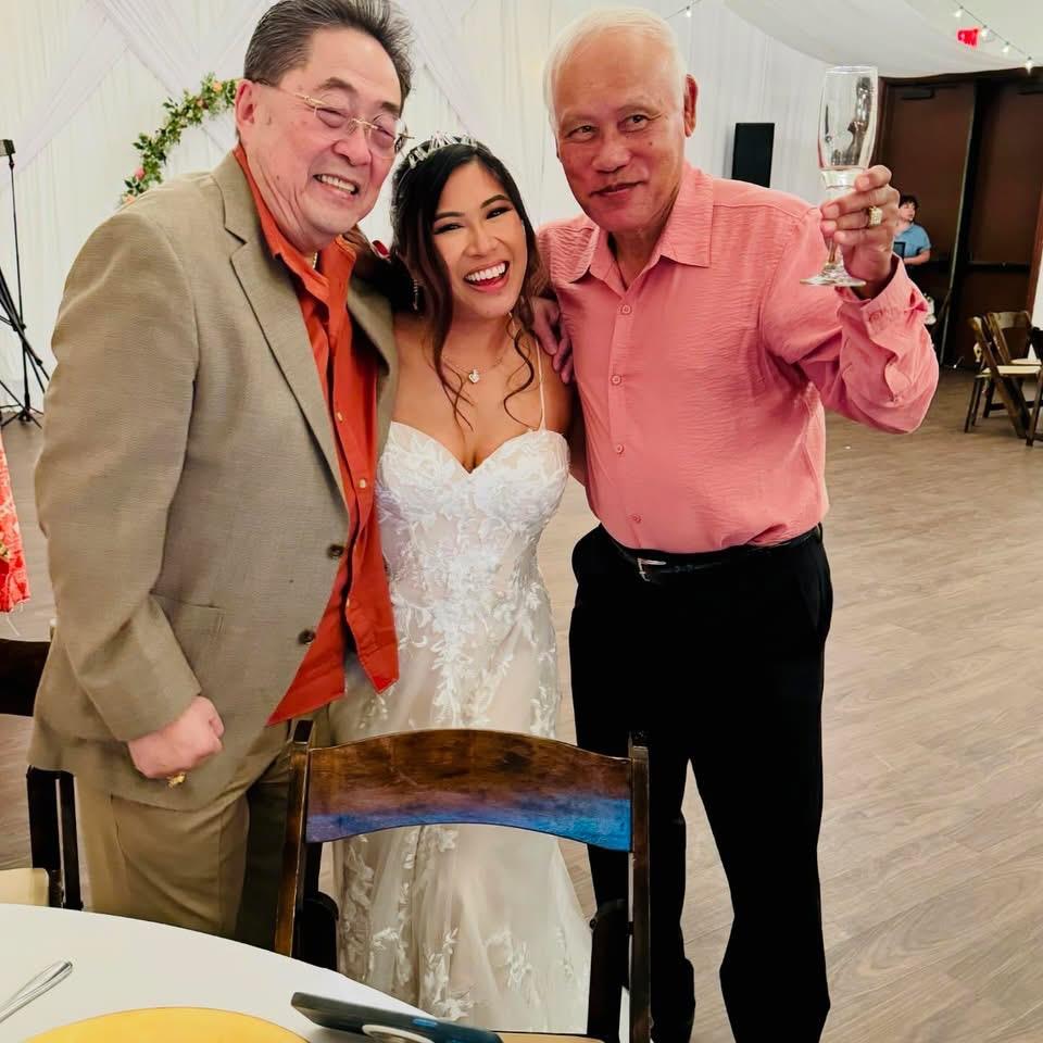 Guests enjoy a joyful moment at a wedding reception with the bride surrounded by family and friends.