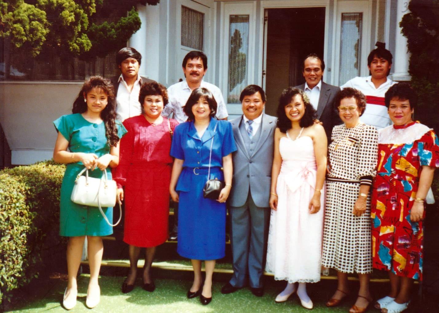 Friends in bright clothes smile for a group photo outside a building.