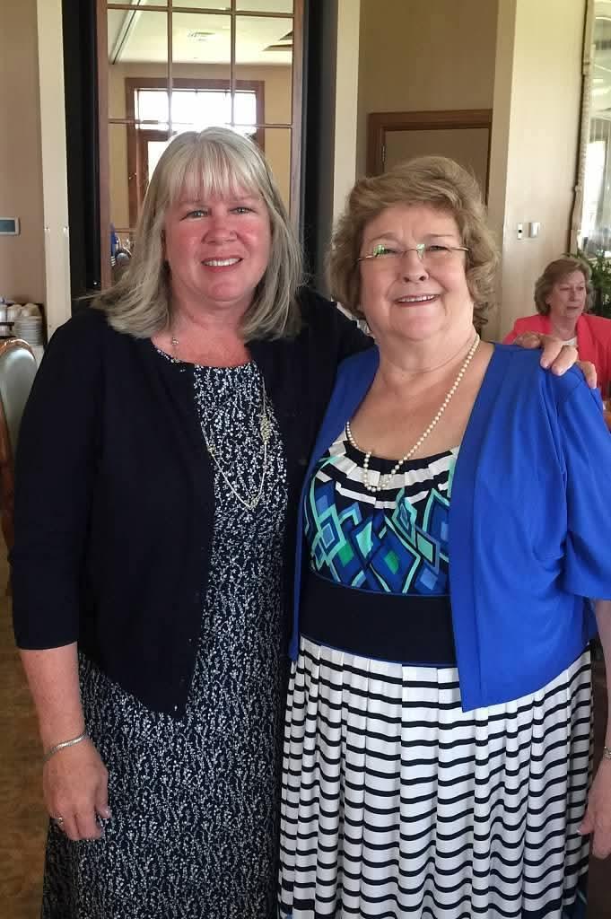 Two women smile warmly as they pose together in a bright and inviting setting.