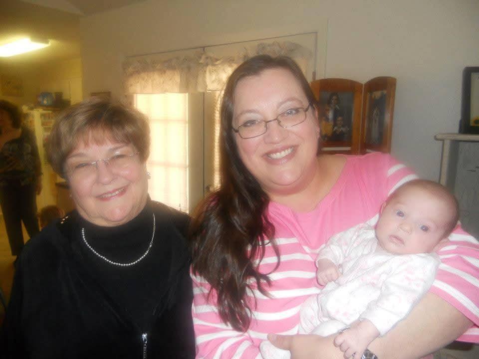 Women share joyful moments with a baby during a family gathering in a warm indoor setting.