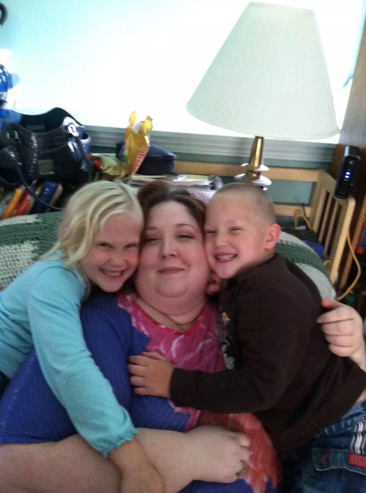 Two children embrace their mother while relaxing together on a cozy couch.