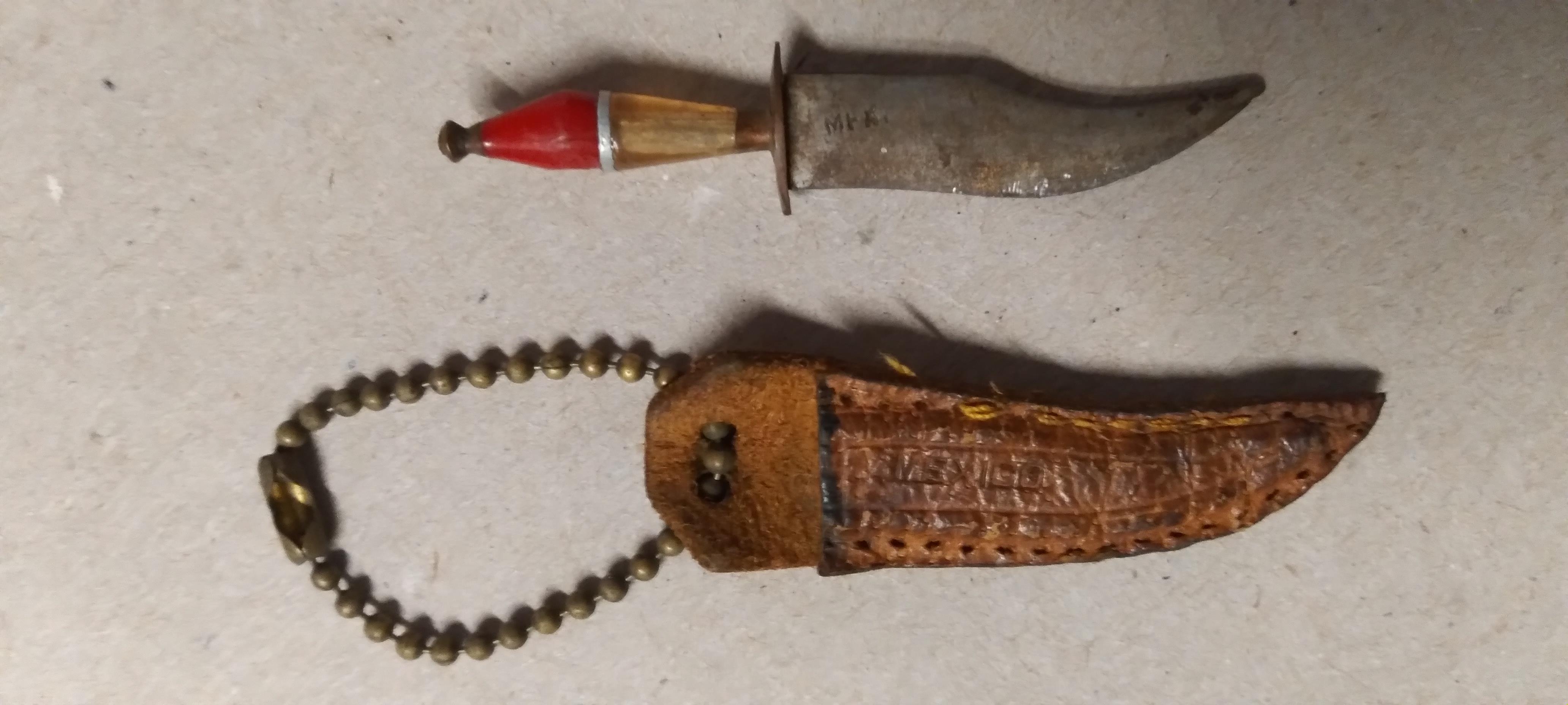 A handcrafted knife with a sheathed handle and decorative beads showcases traditional craftsmanship.