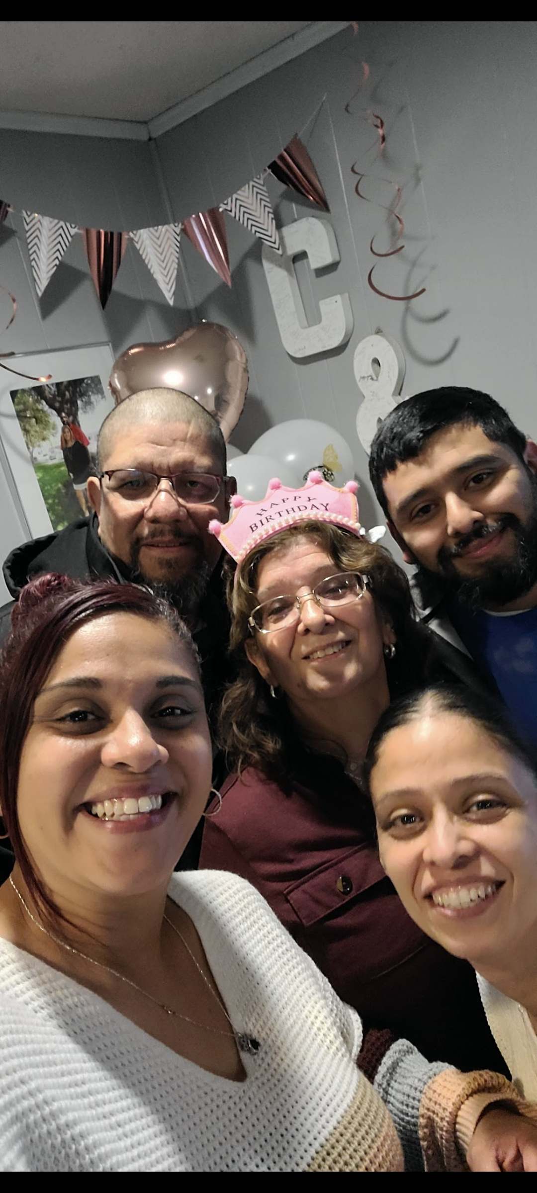 Joyful family members pose together with festive attire and decorations, celebrating an event.