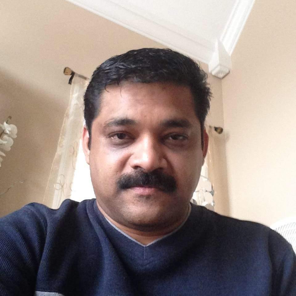 A man wearing a sweater is taking a close-up selfie in a cozy indoor space.