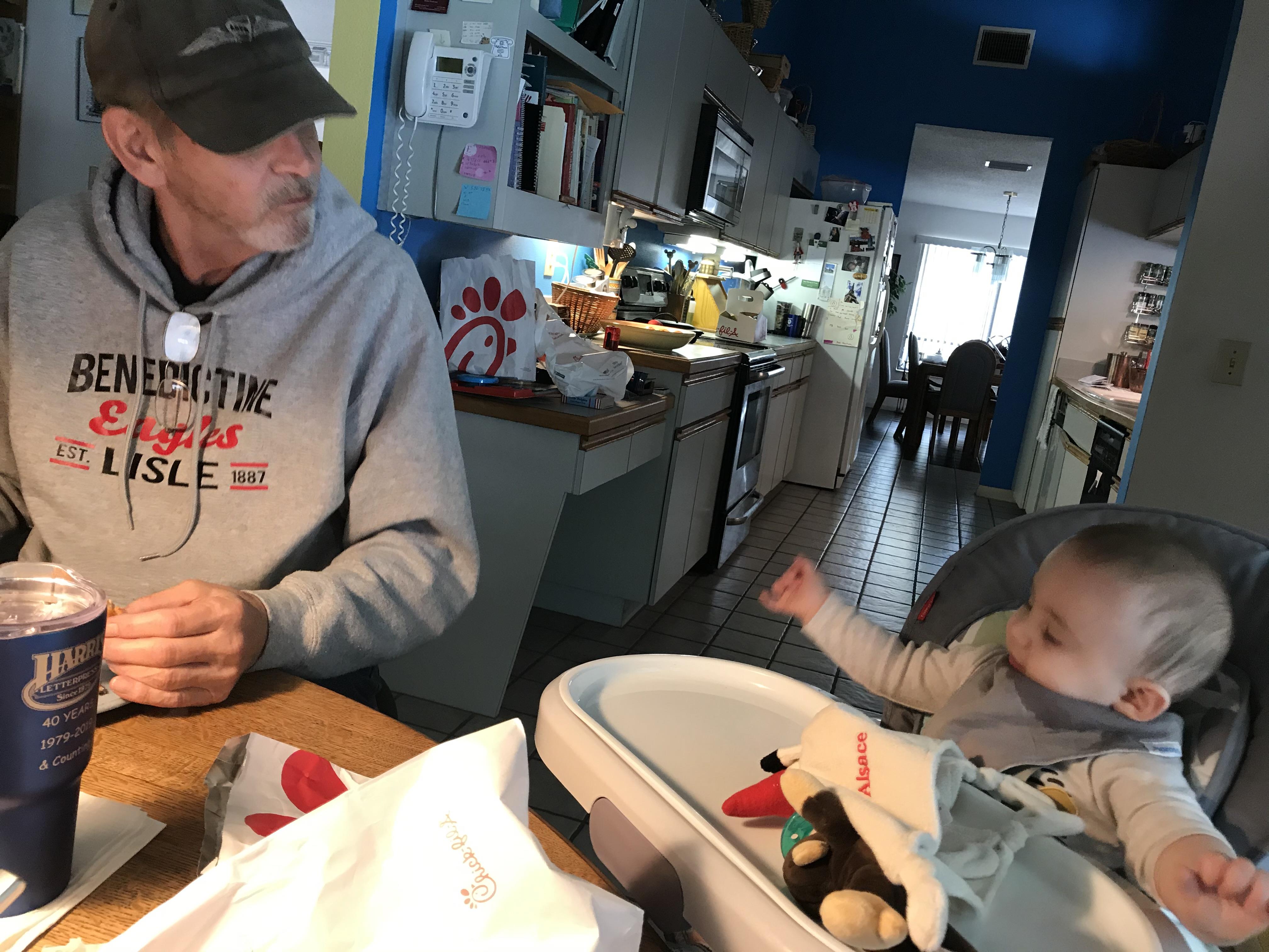 Grandfather and grandchild share a delightful breakfast moment in a bright kitchen.