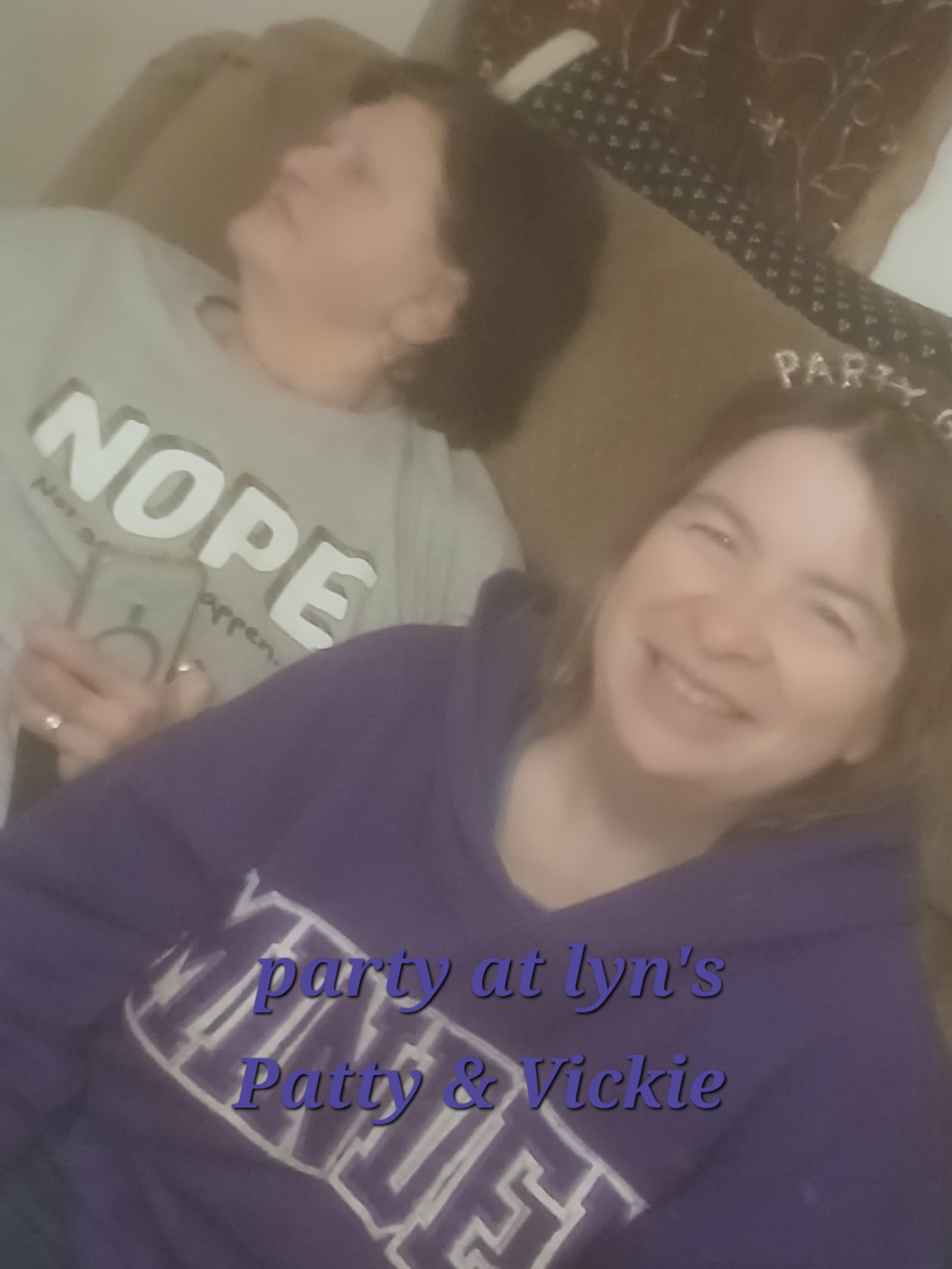 Two friends relax together at Lyn's house, sharing laughter and drinks during a fun evening.