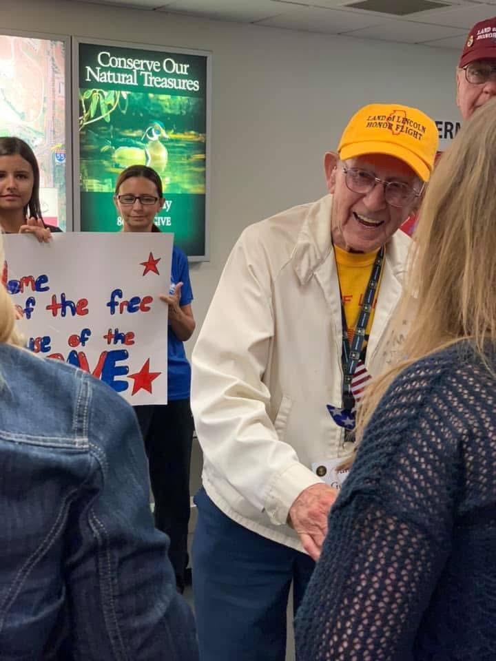 A cheerful veteran interacts with attendees at a community event, promoting Veterans Day.