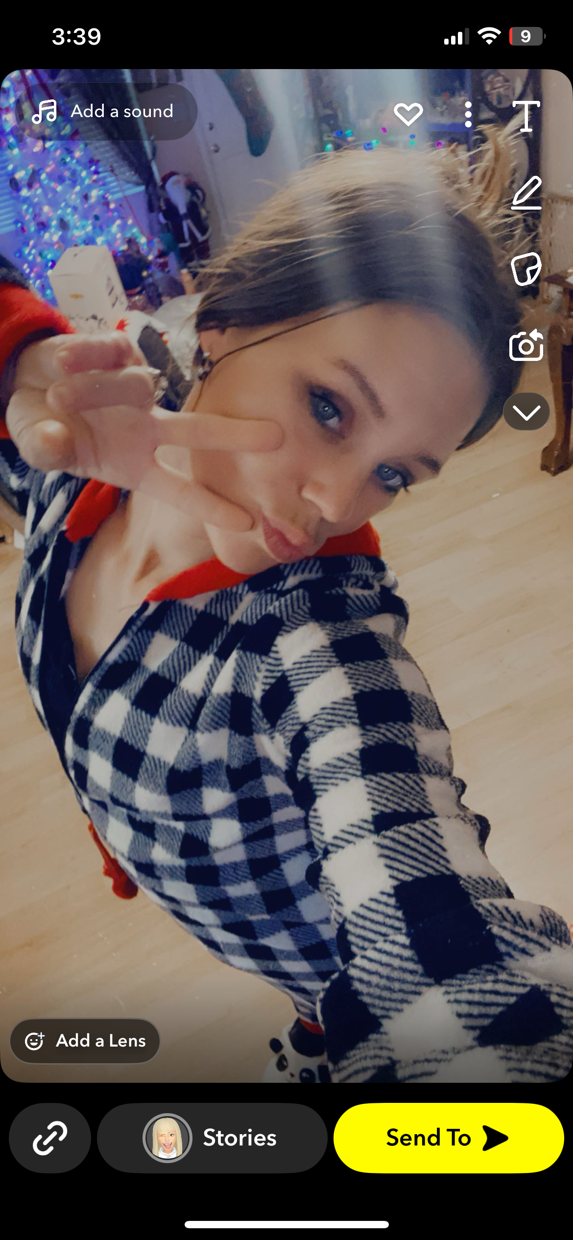 Young woman smiles and poses with a peace sign, wearing checkered pajamas at home.