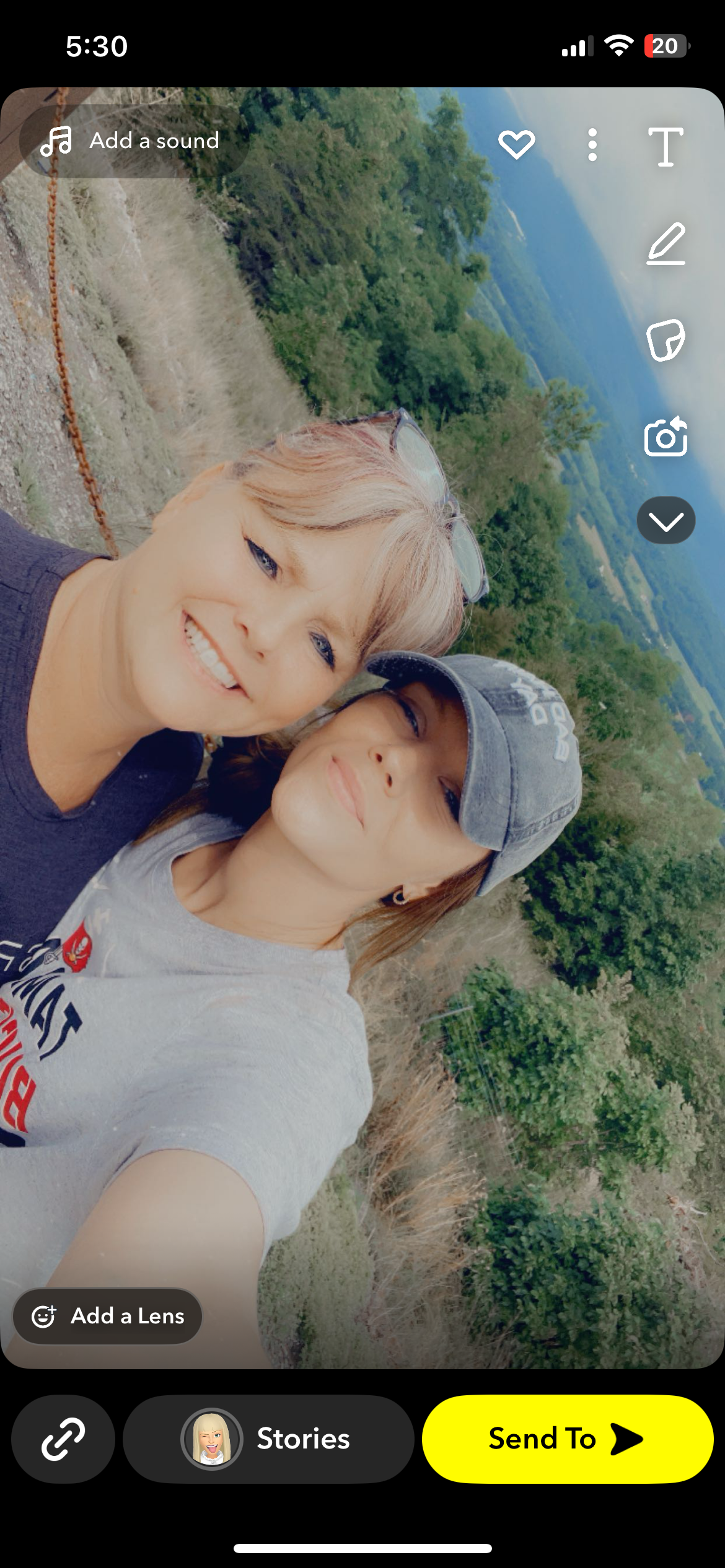 Two women smile together, capturing a moment in a beautiful green outdoor setting.