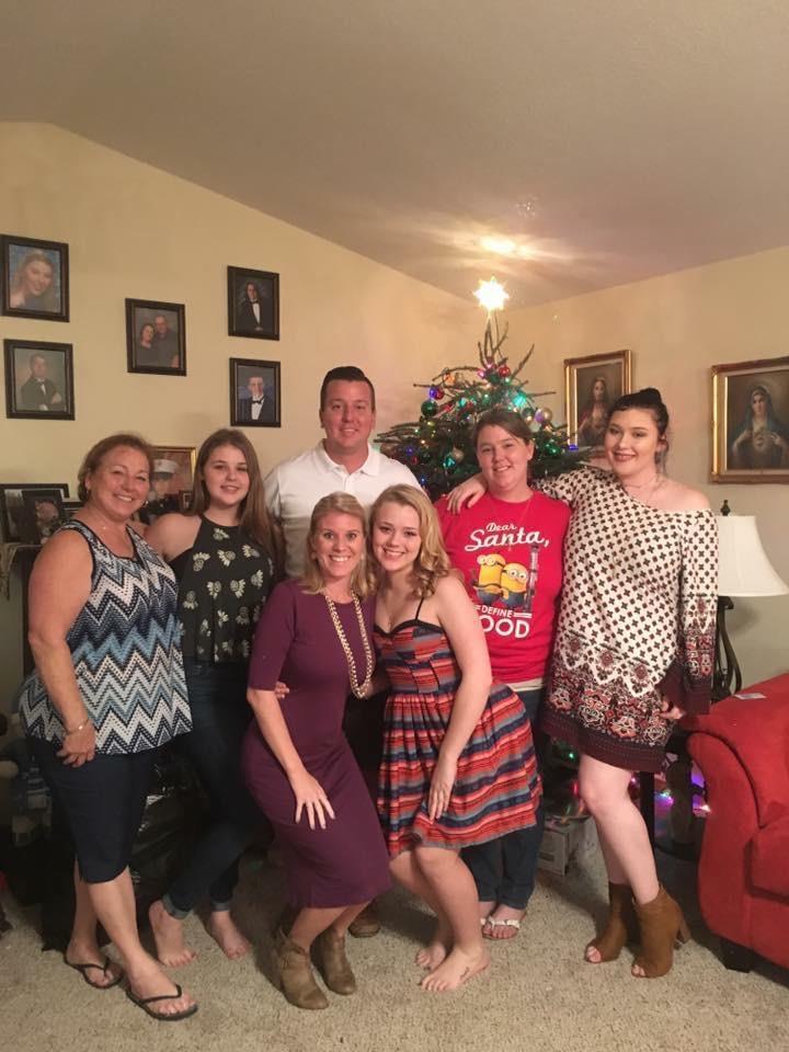 A joyful family gathering takes place with a beautifully decorated Christmas tree in the background.