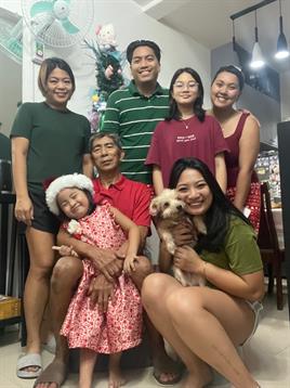 A joyful family poses together in holiday outfits, celebrating with smiles and a dog.