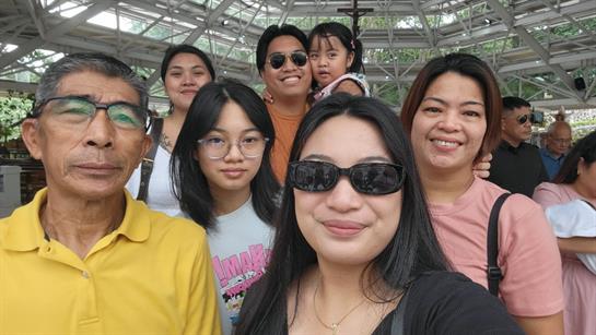 Family members gather together, smiling and enjoying a sunny day at a spacious outdoor venue.