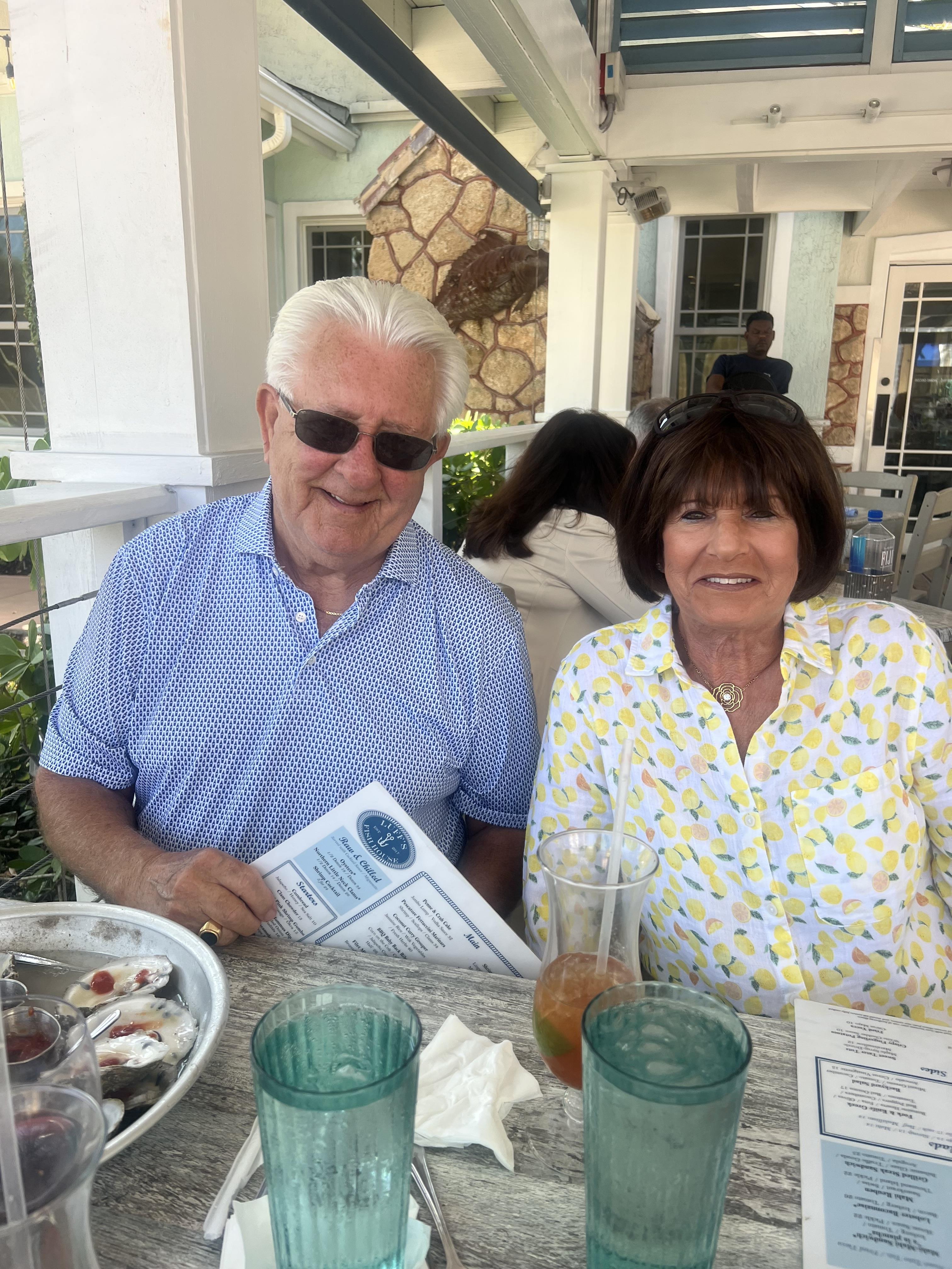 Couple relaxes at a restaurant, smiling and sharing a meal while enjoying the beautiful day.