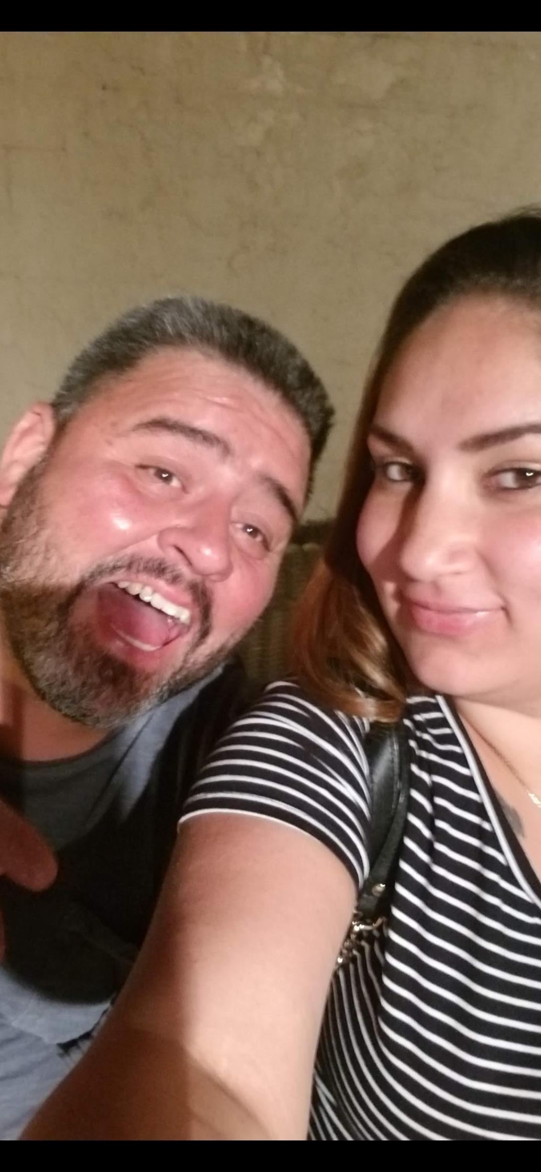 Smiling couple poses closely together, sharing laughter and joy in a warm environment.