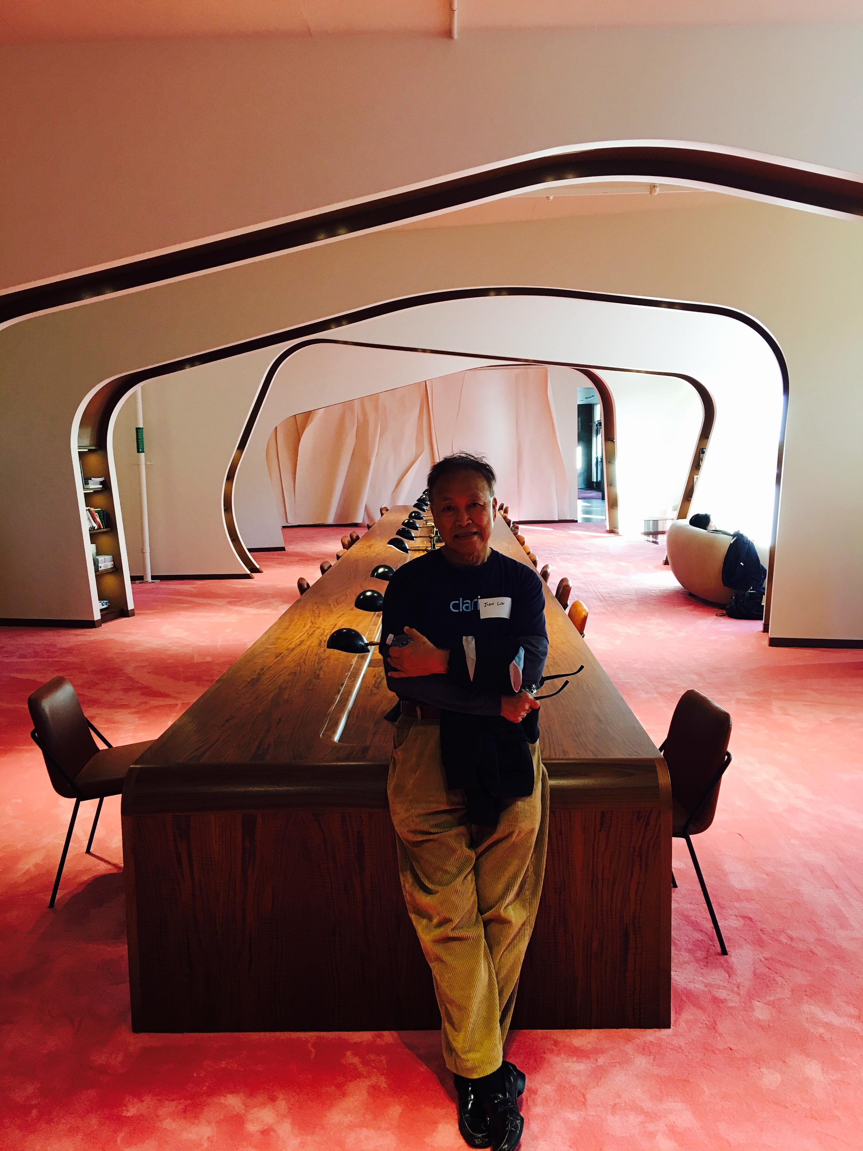 A person stands casually in a beautifully designed workspace featuring unique architectural lines.