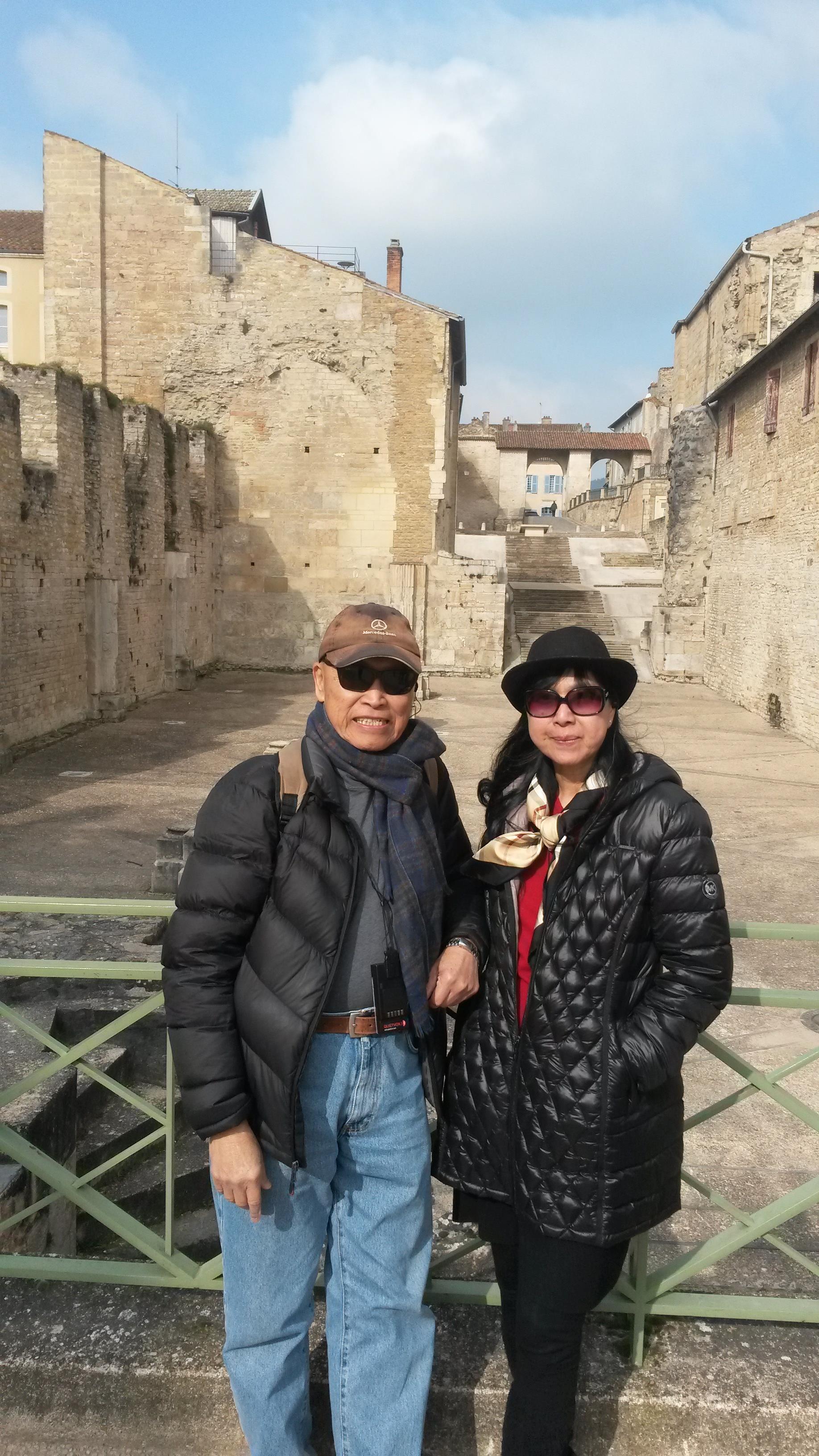 A couple enjoys their visit to historic ruins under a clear sky, showcasing their smiles.