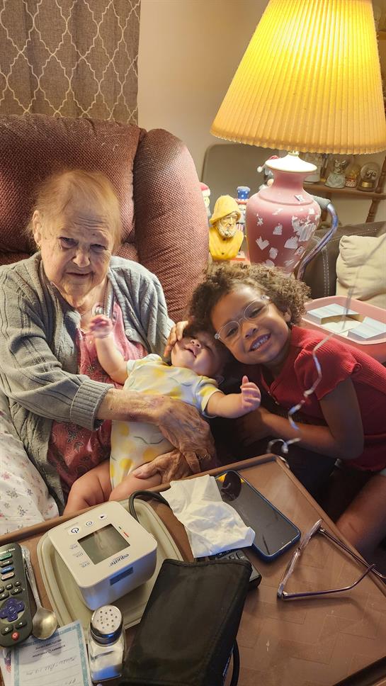 An older woman holding a baby and a younger girl