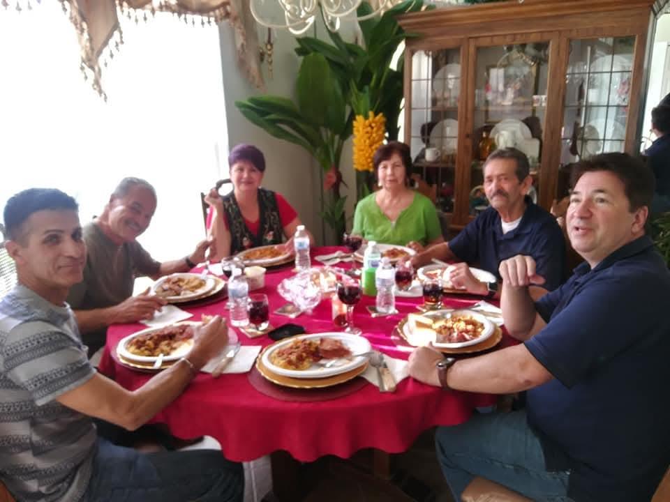 Friends and family share laughs and delicious food around a table filled with plates and drinks.