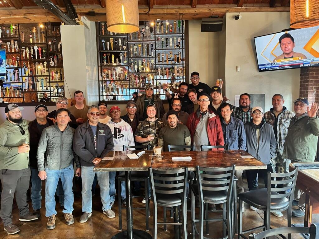 A large group of friends gathers at a local restaurant, enjoying drinks and good company after work.