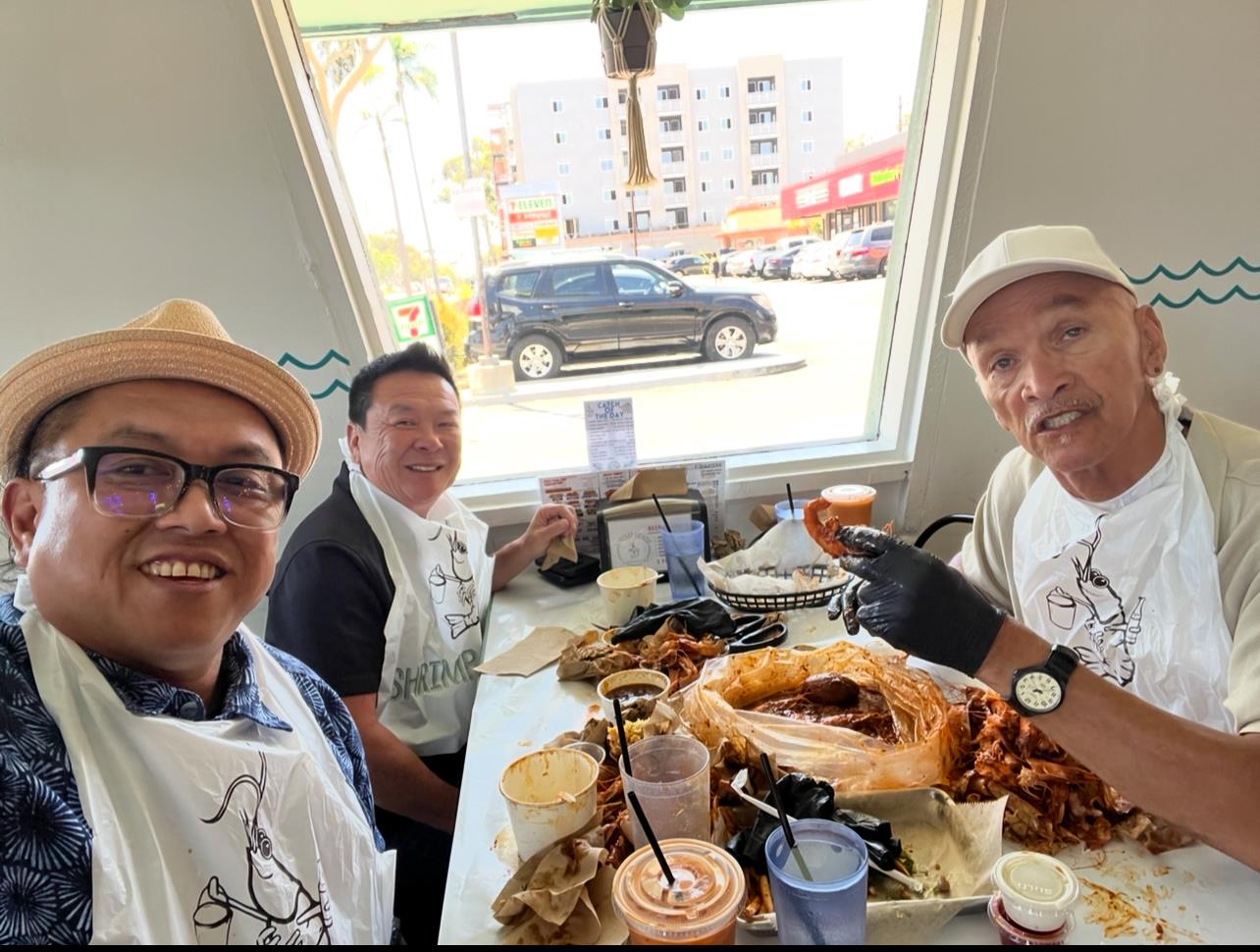 Three friends share a lively meal at a seafood restaurant, surrounded by empty plates.