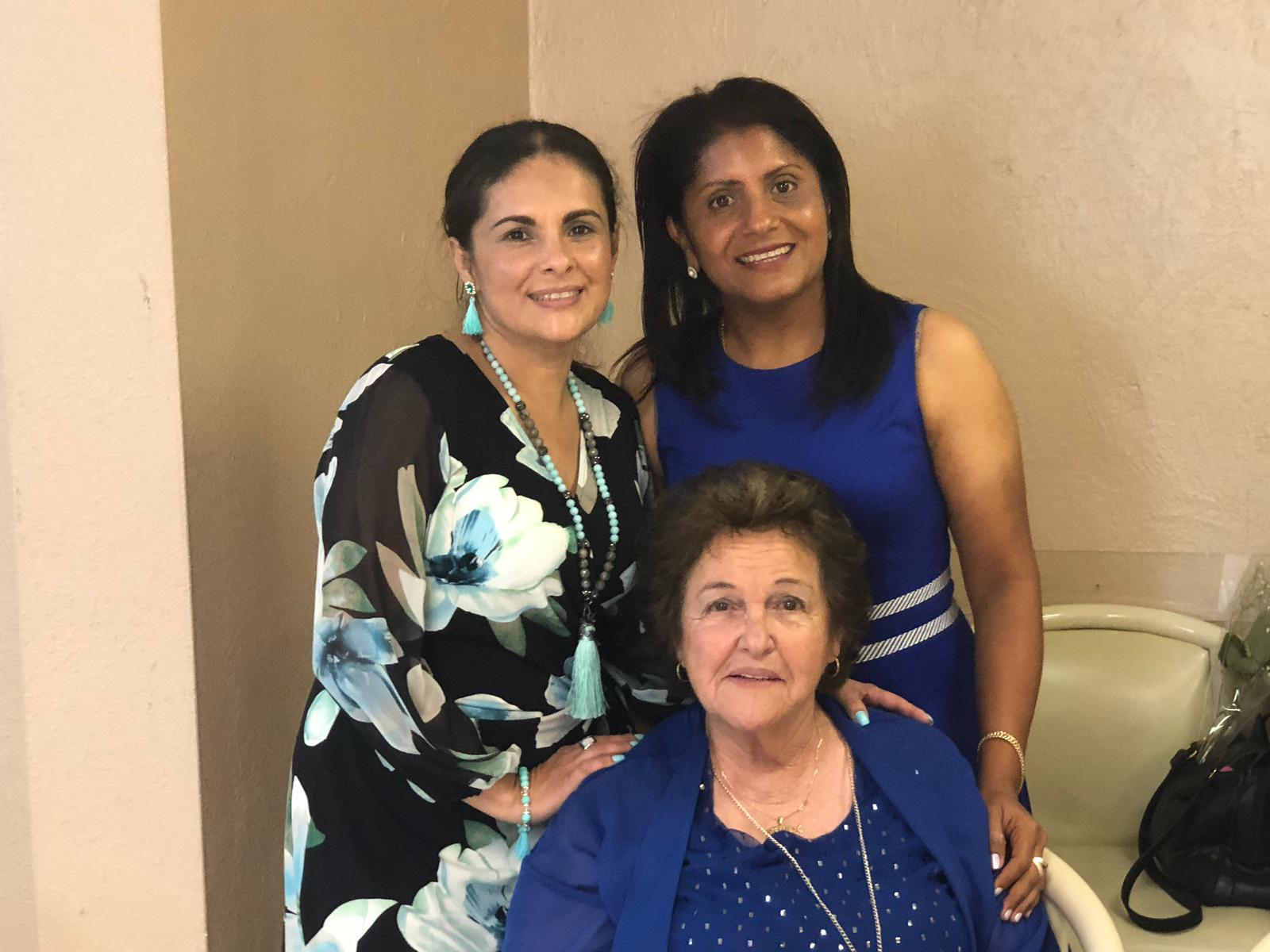 Three women pose for a cheerful moment at a family event, enjoying their time together.