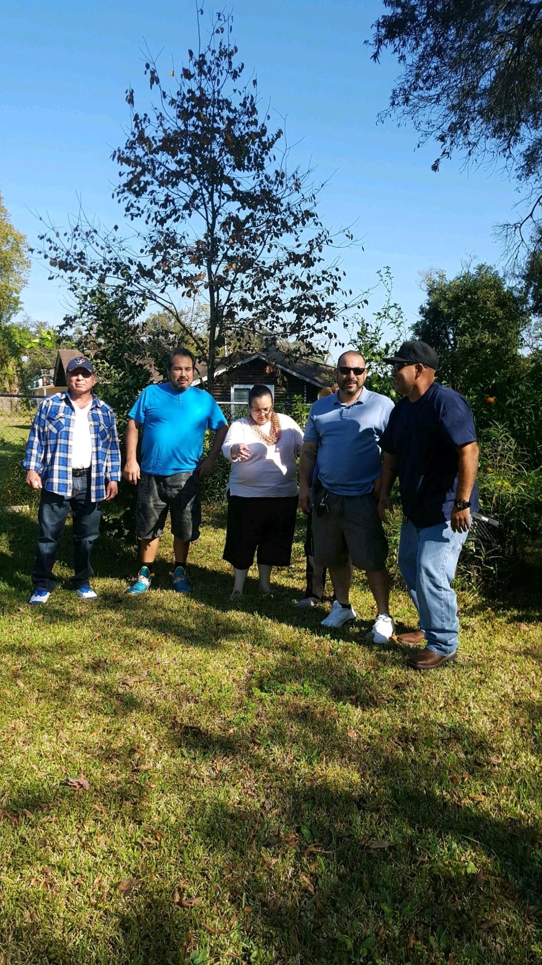 Five friends stand together in a garden, enjoying the sunny weather and each other's company.