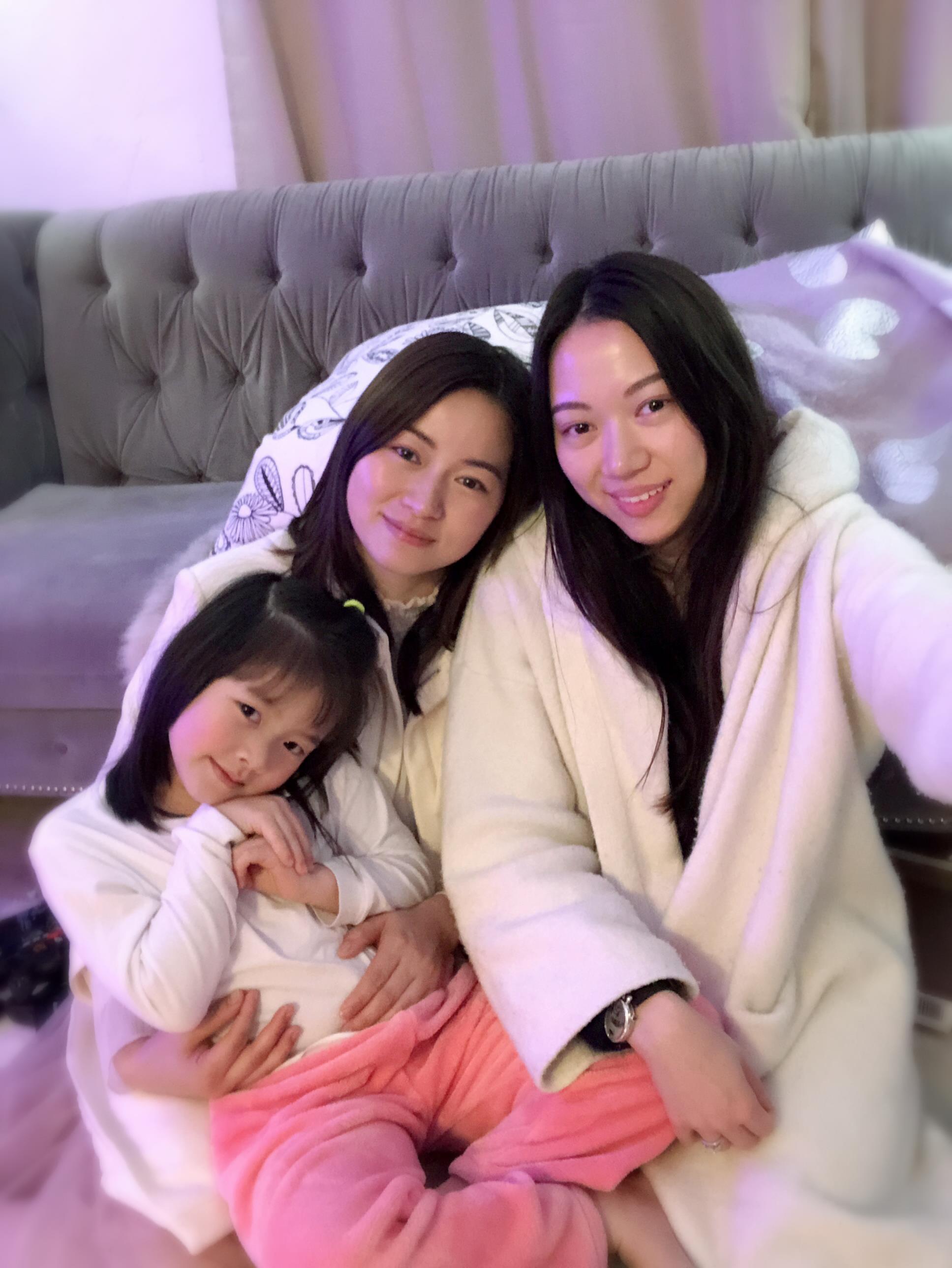Three family members are relaxing indoors in matching loungewear, sharing smiles and warmth.