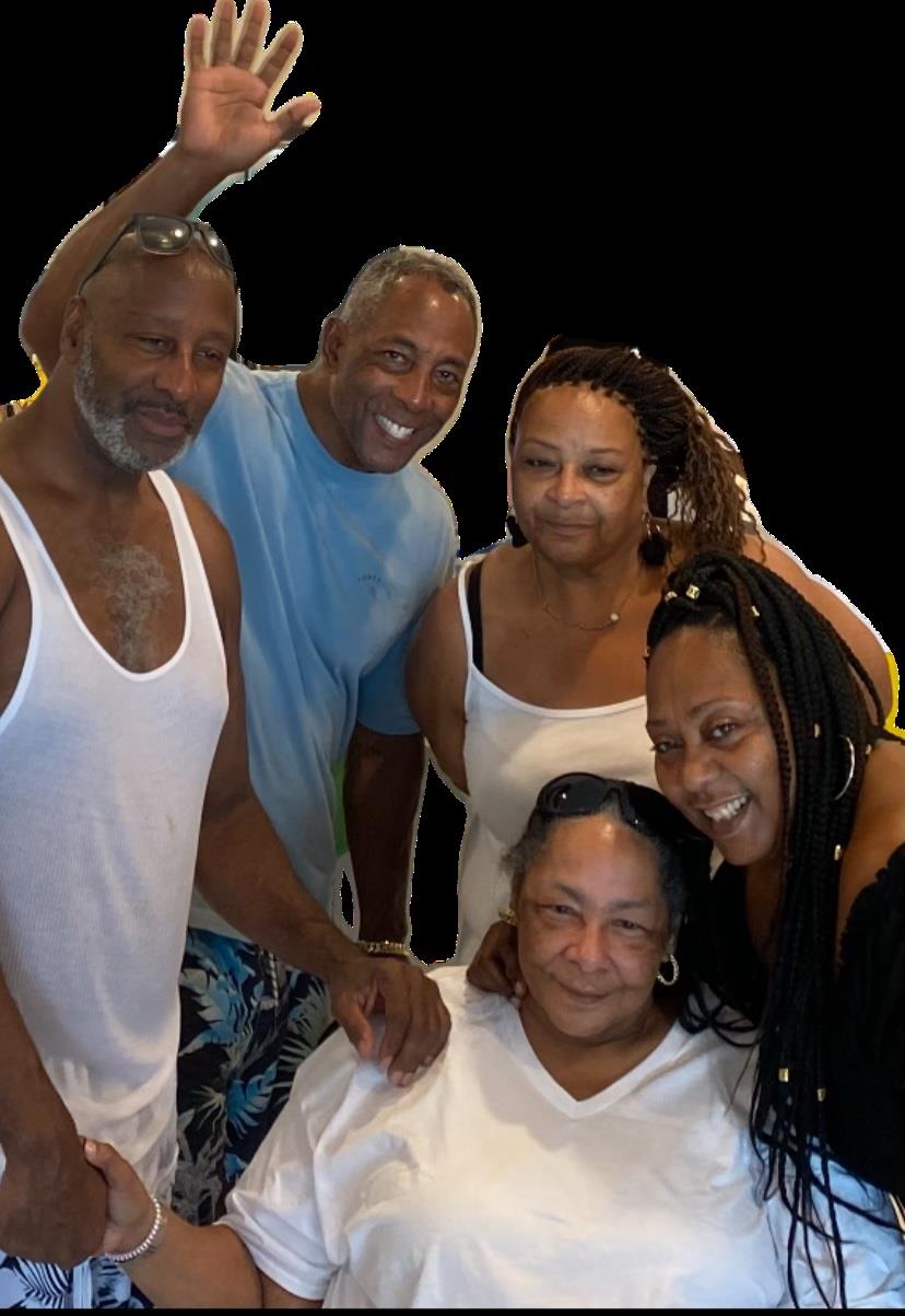 A group of five family members shares smiles and laughter while celebrating indoors.
