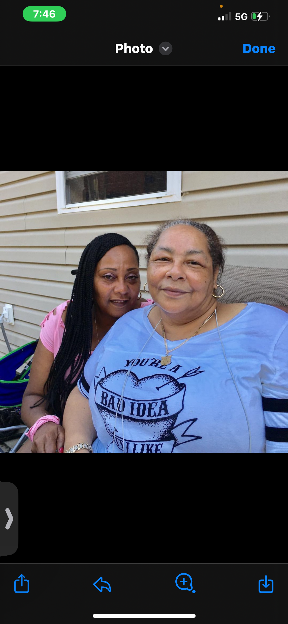 Two women share smiles while relaxing on a porch during a warm afternoon gathering.