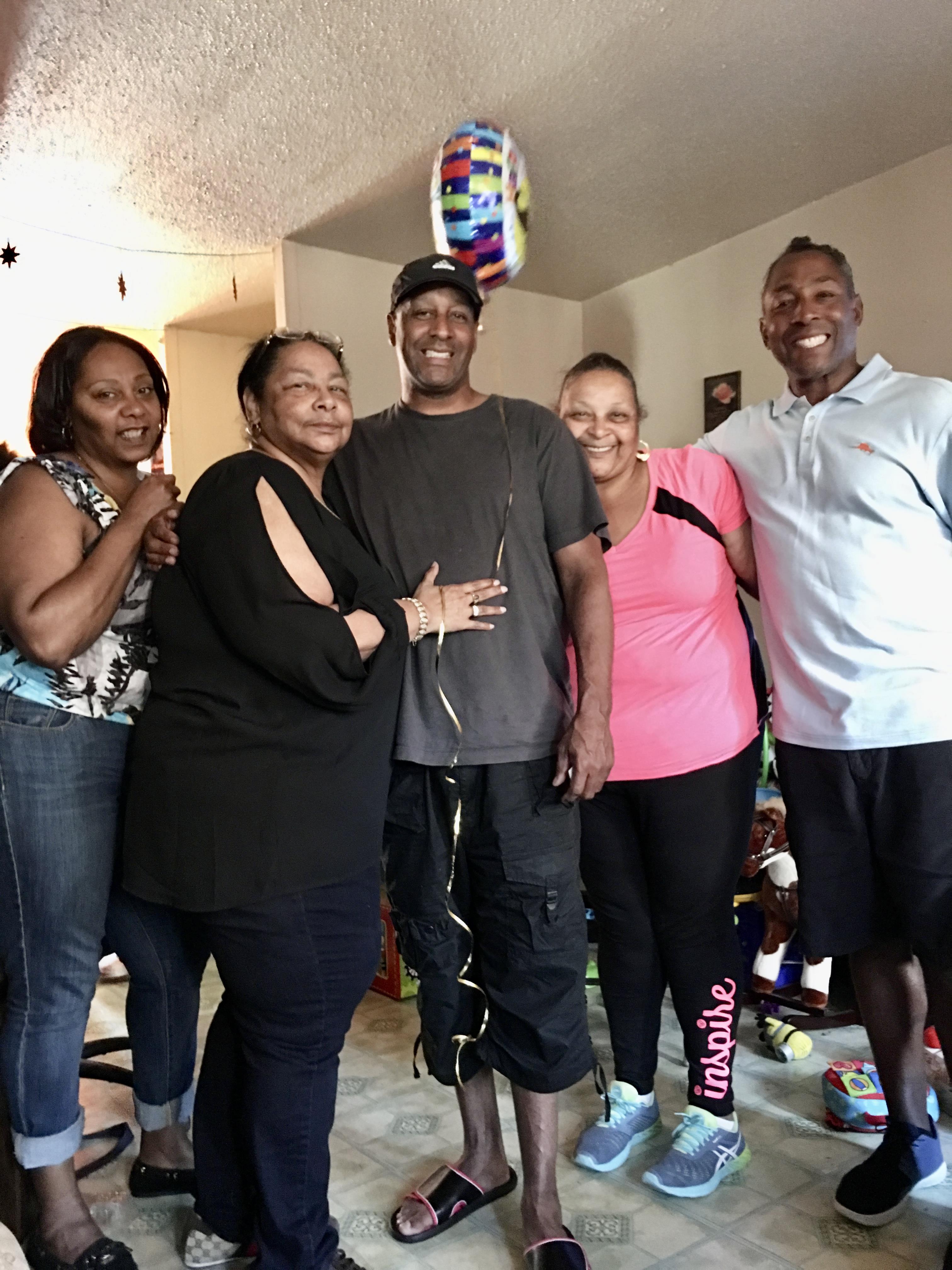 Five friends gather in a warm living room, sharing smiles and joy during a celebration.