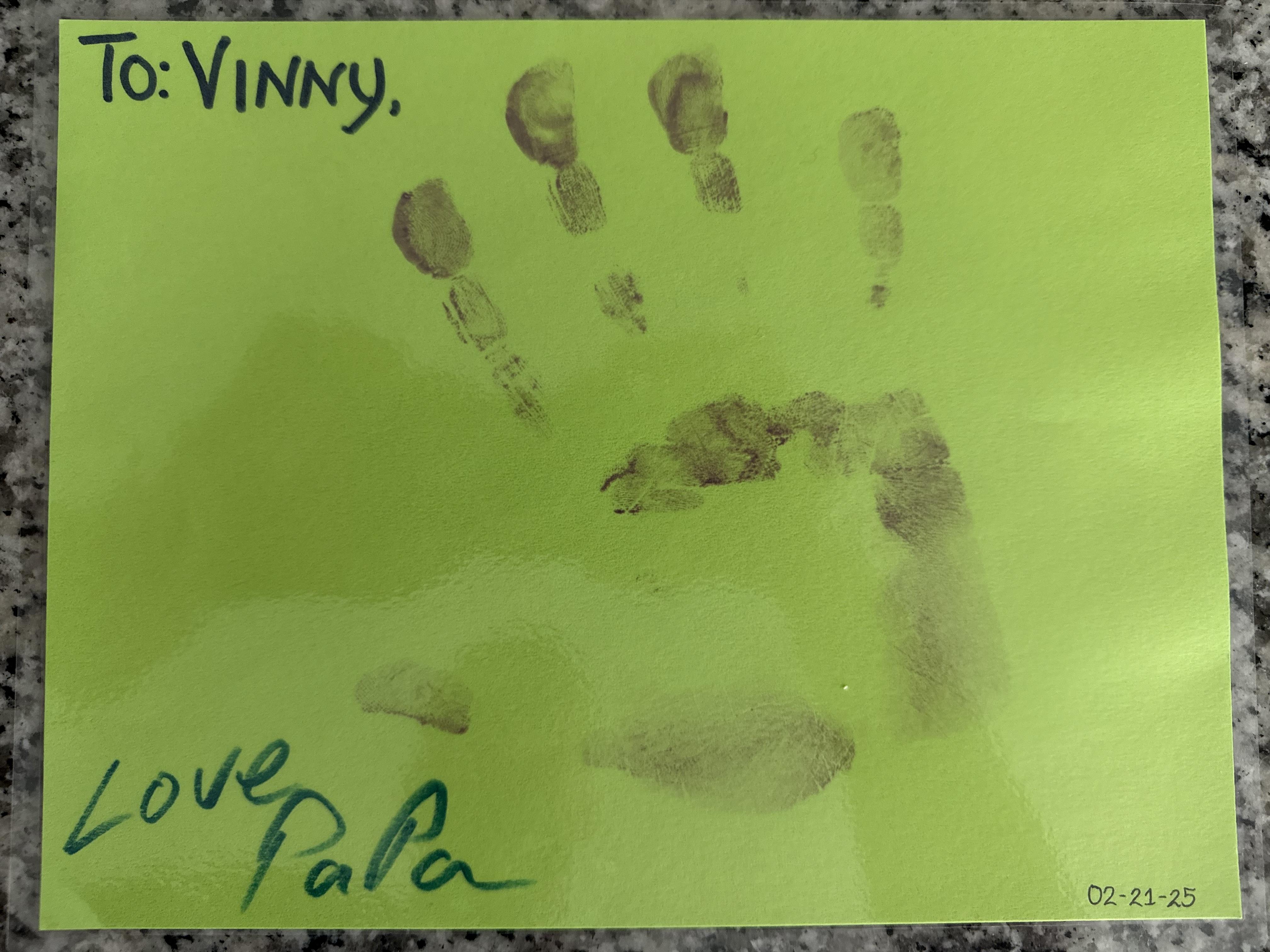 A personalized card features a handprint in green, conveying a heartfelt message to Vinny from Papa.