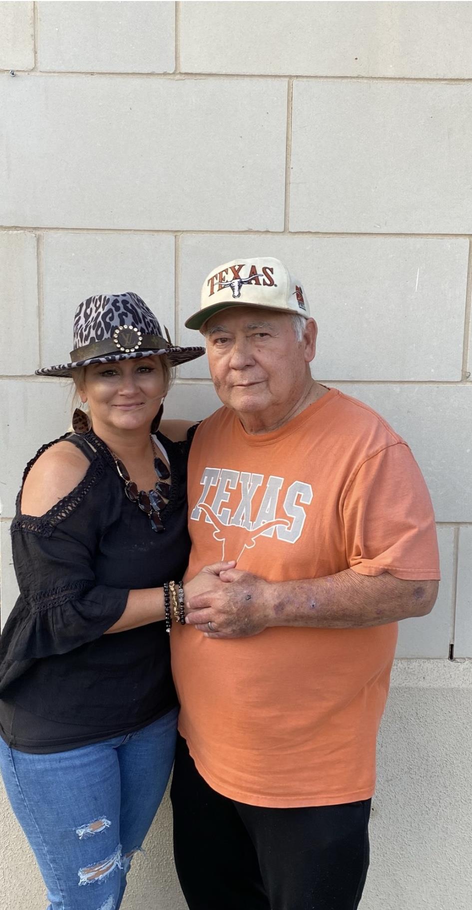A woman smiles while holding hands with an elderly man, showcasing warmth and connection in Texas.