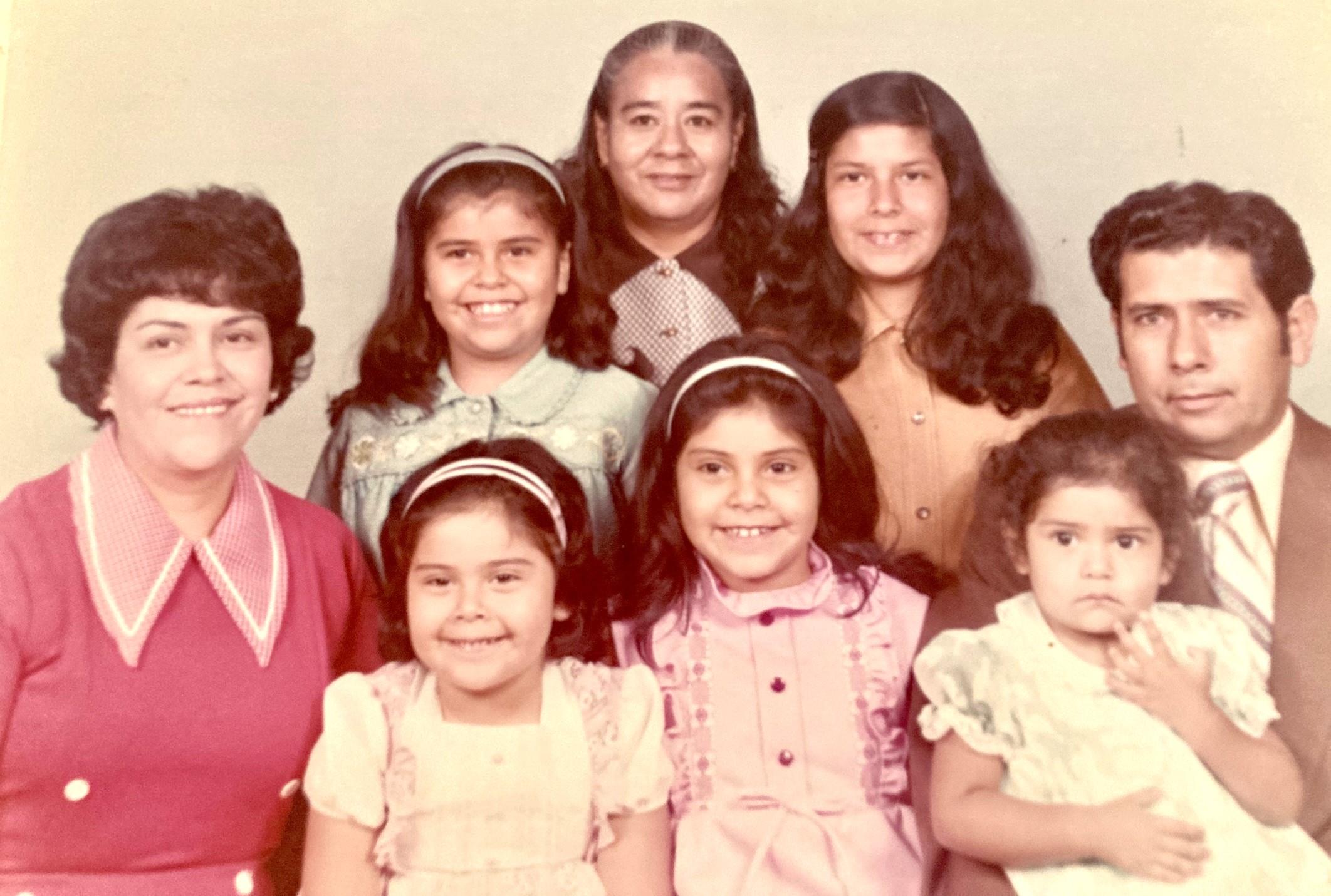 A family poses together in a studio, showcasing multiple generations and joyful expressions.