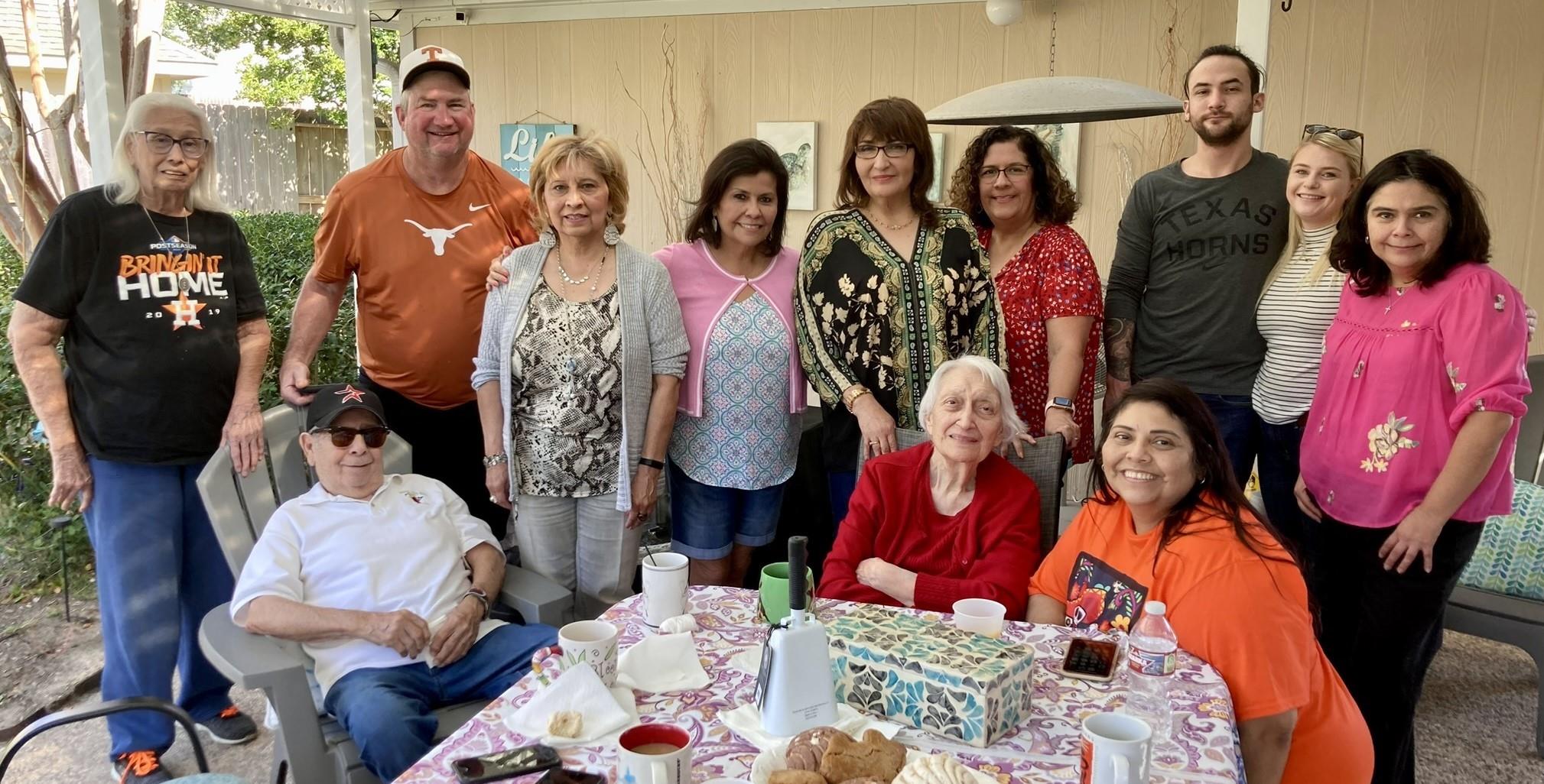 Friends and family share laughter and stories over food on a sunny day.