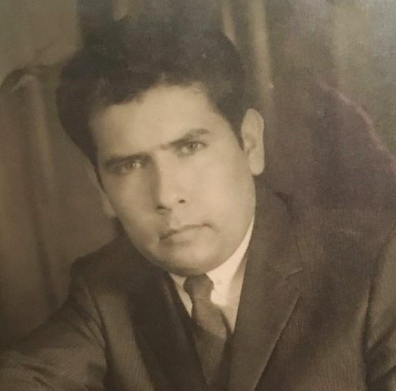 A man in a formal suit exudes charisma with a serious expression in a vintage setting.