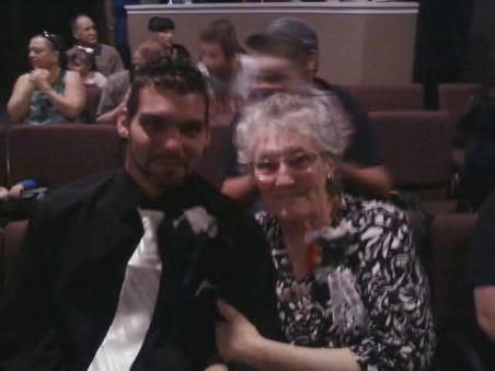 A young man and an elderly woman share a moment of happiness amidst a lively family gathering.