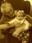 Elderly woman joyfully cradles her grandchild in a comfortable setting filled with love.