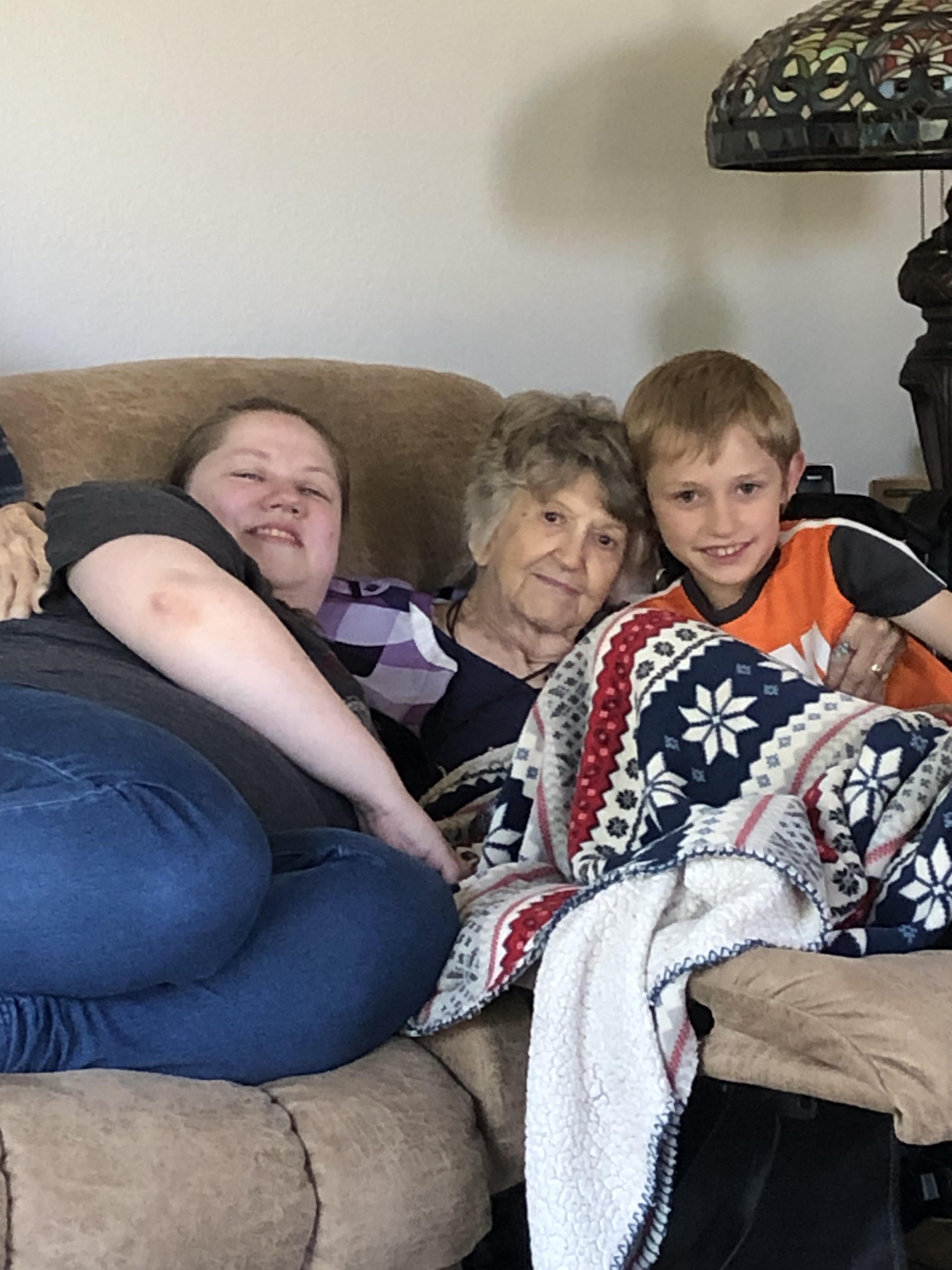 Three generations gather on the couch to share warmth and laughter while spending quality time.