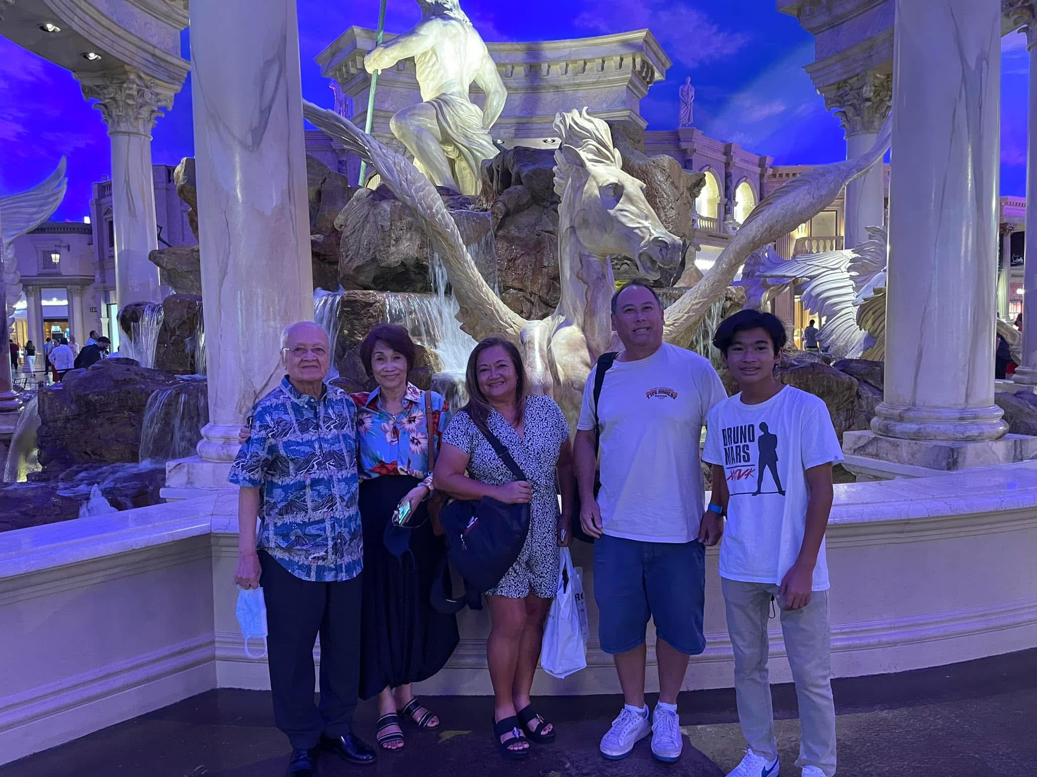 Five individuals gather together at a stunning fountain in Las Vegas under a vibrant sky.