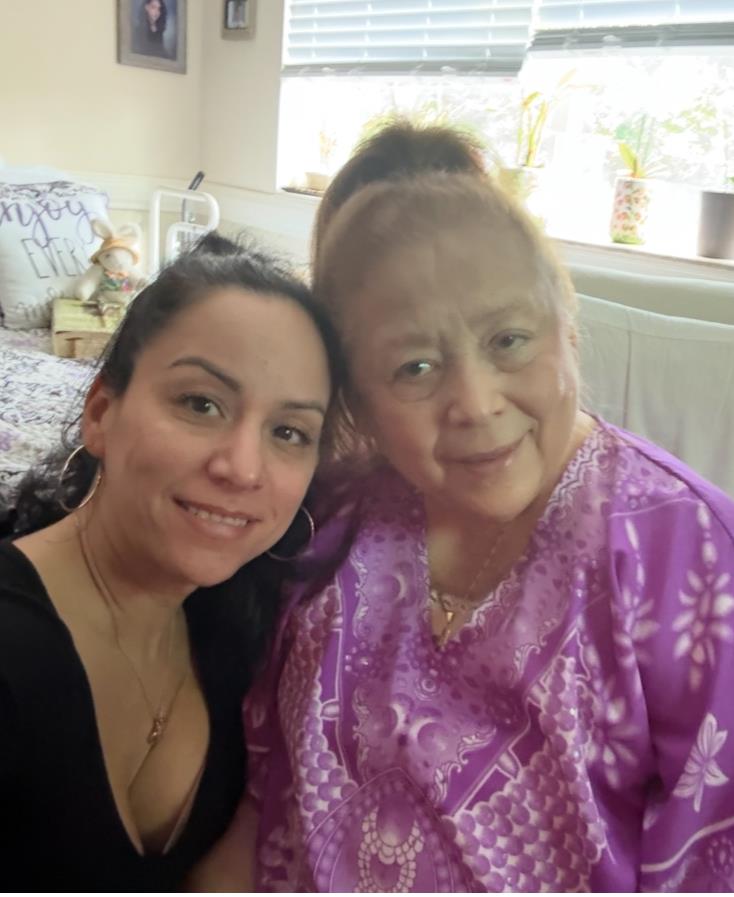 Two women share smiles in a bright living room, enjoying quality time among decor and plants.