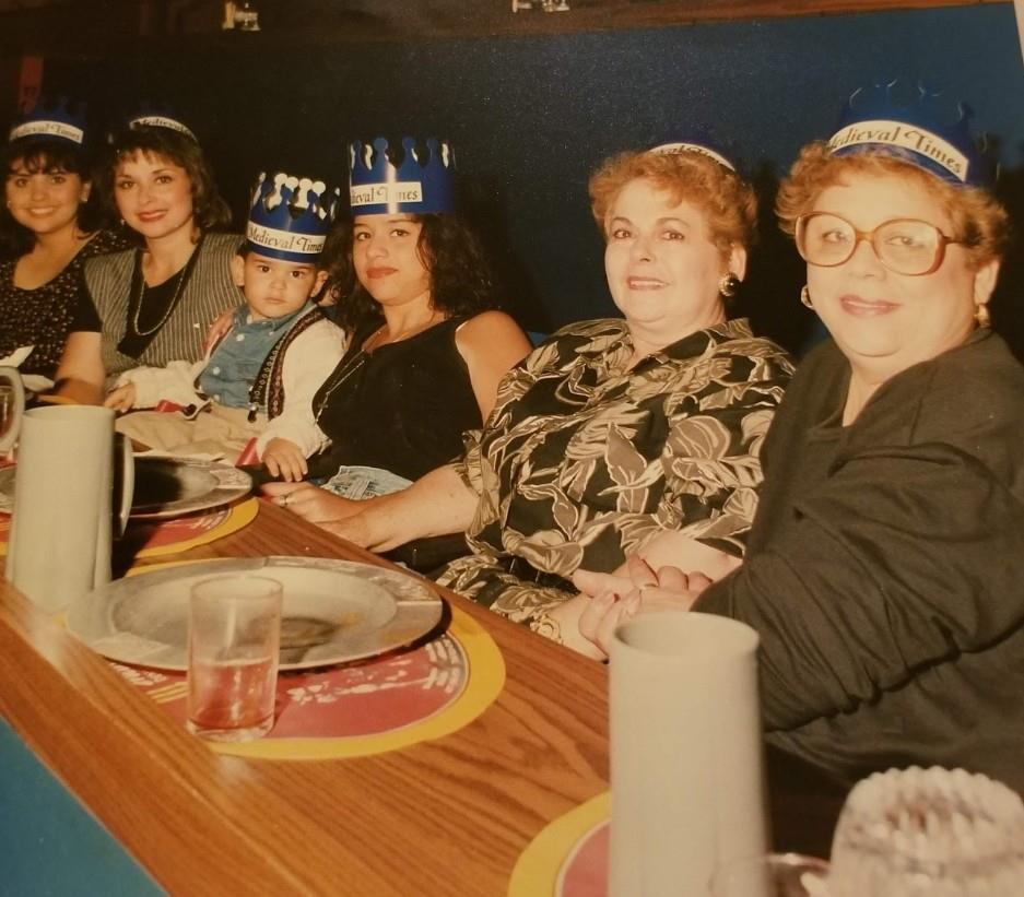 A joyful gathering of women in party hats enjoying a meal together at a restaurant.