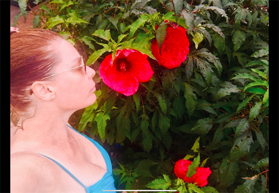 A woman in a blue dress smelling a flower